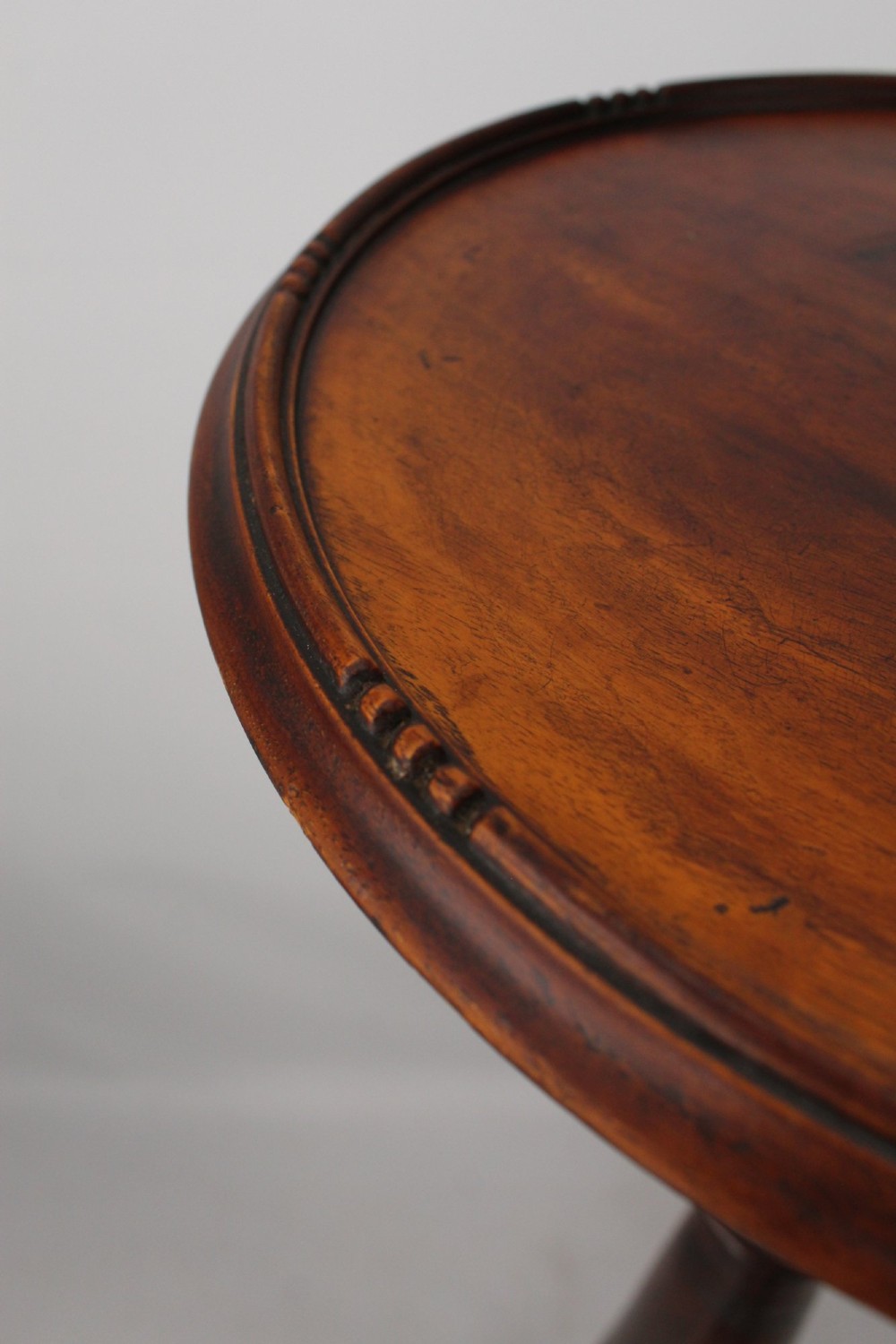 A tall Edwardian mahogany plant stand with a circular top, carved acanthus leaf column, and a tripod base. View VI