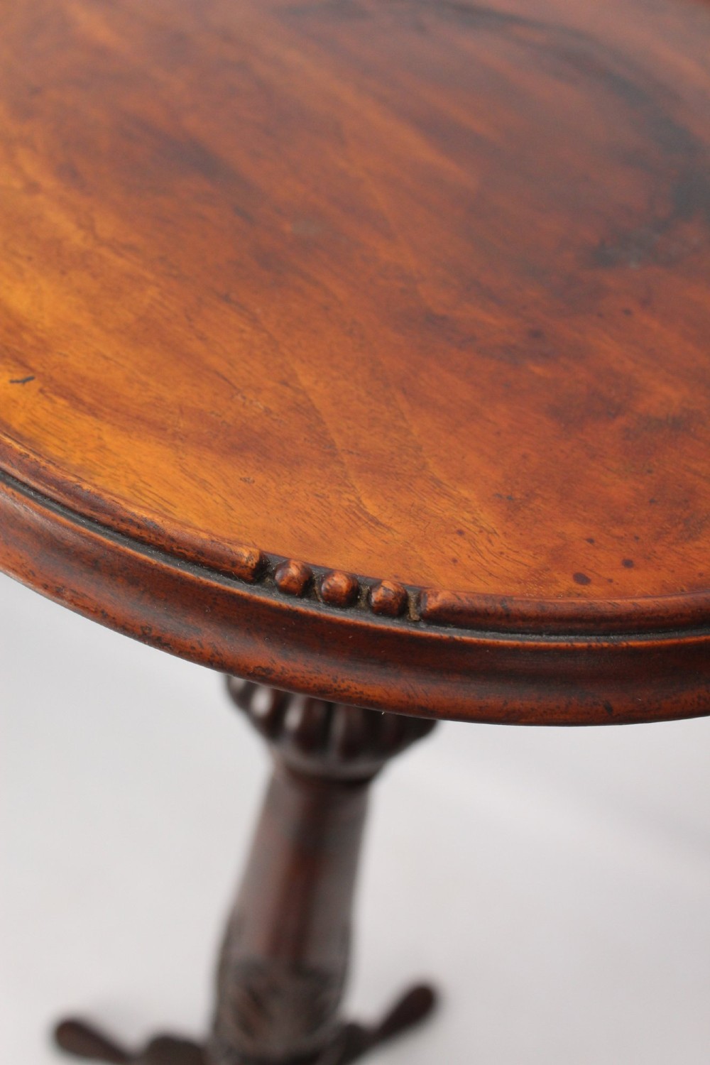 A tall Edwardian mahogany plant stand with a circular top, carved acanthus leaf column, and a tripod base. View VII