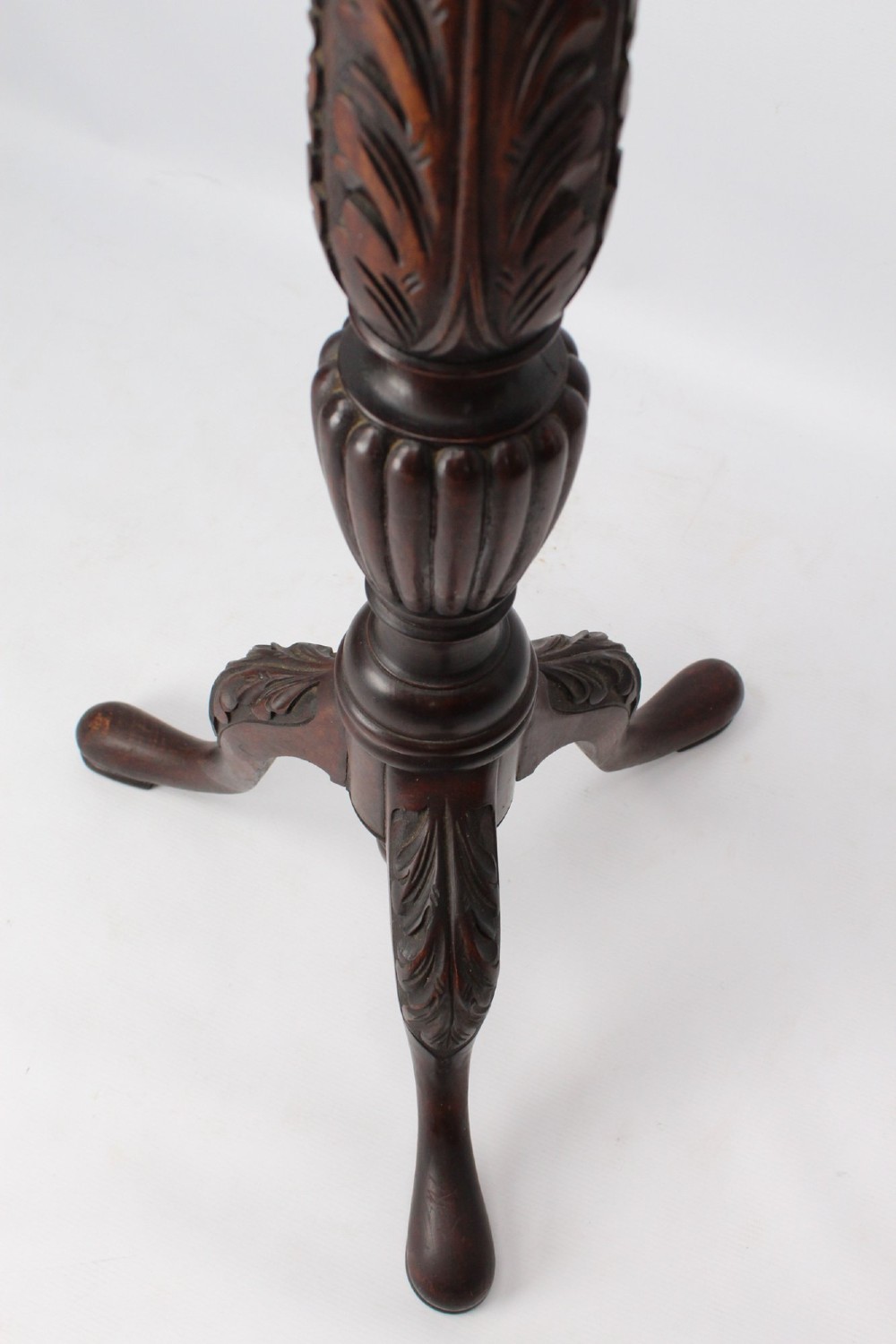 A tall Edwardian mahogany plant stand with a circular top, carved acanthus leaf column, and a tripod base. View X