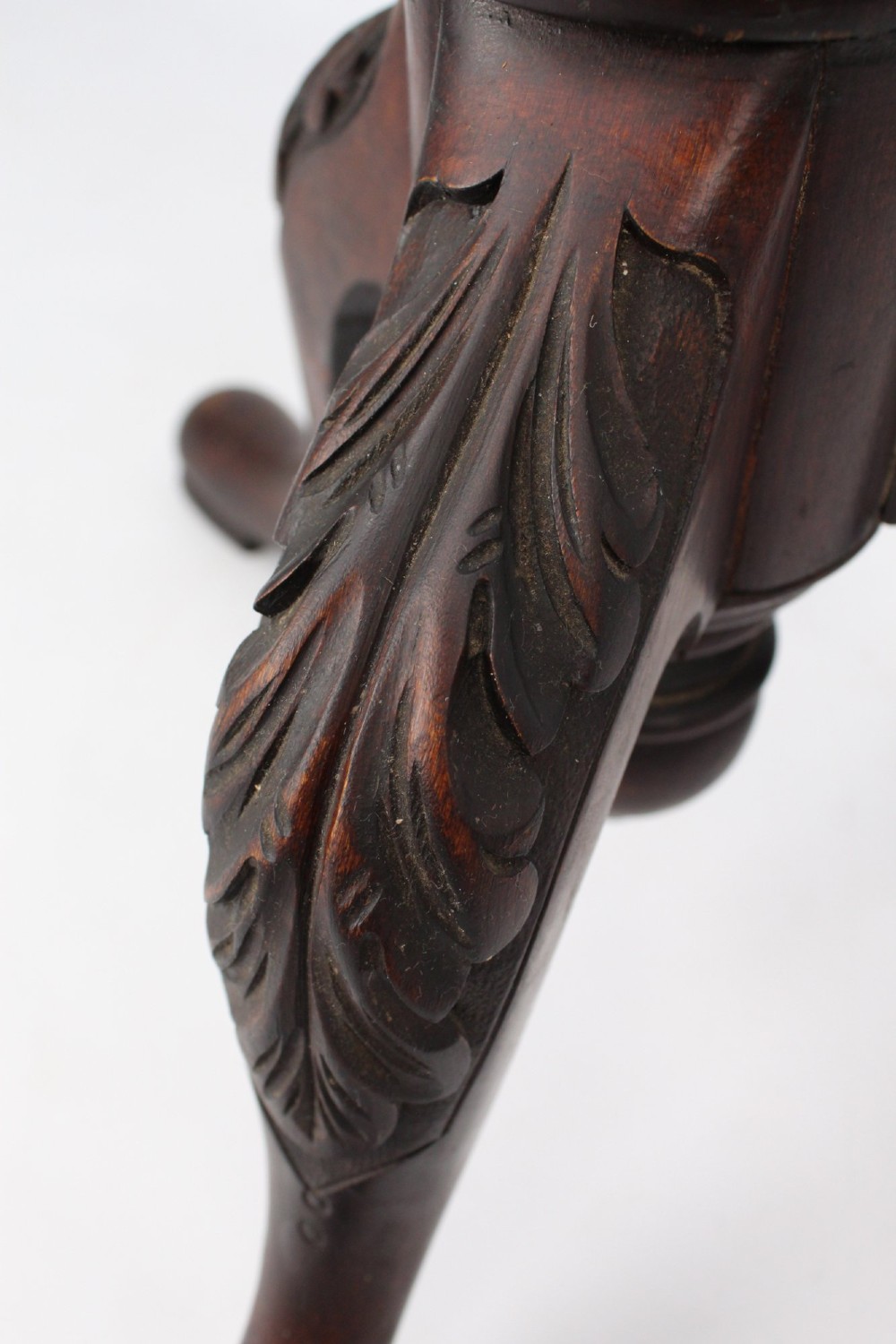A tall Edwardian mahogany plant stand with a circular top, carved acanthus leaf column, and a tripod base. View XI