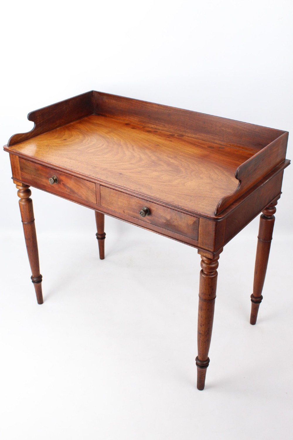 A Victorian mahogany writing table featuring a low gallery back top, two frieze drawers with decorative handles, and four turned legs. View II