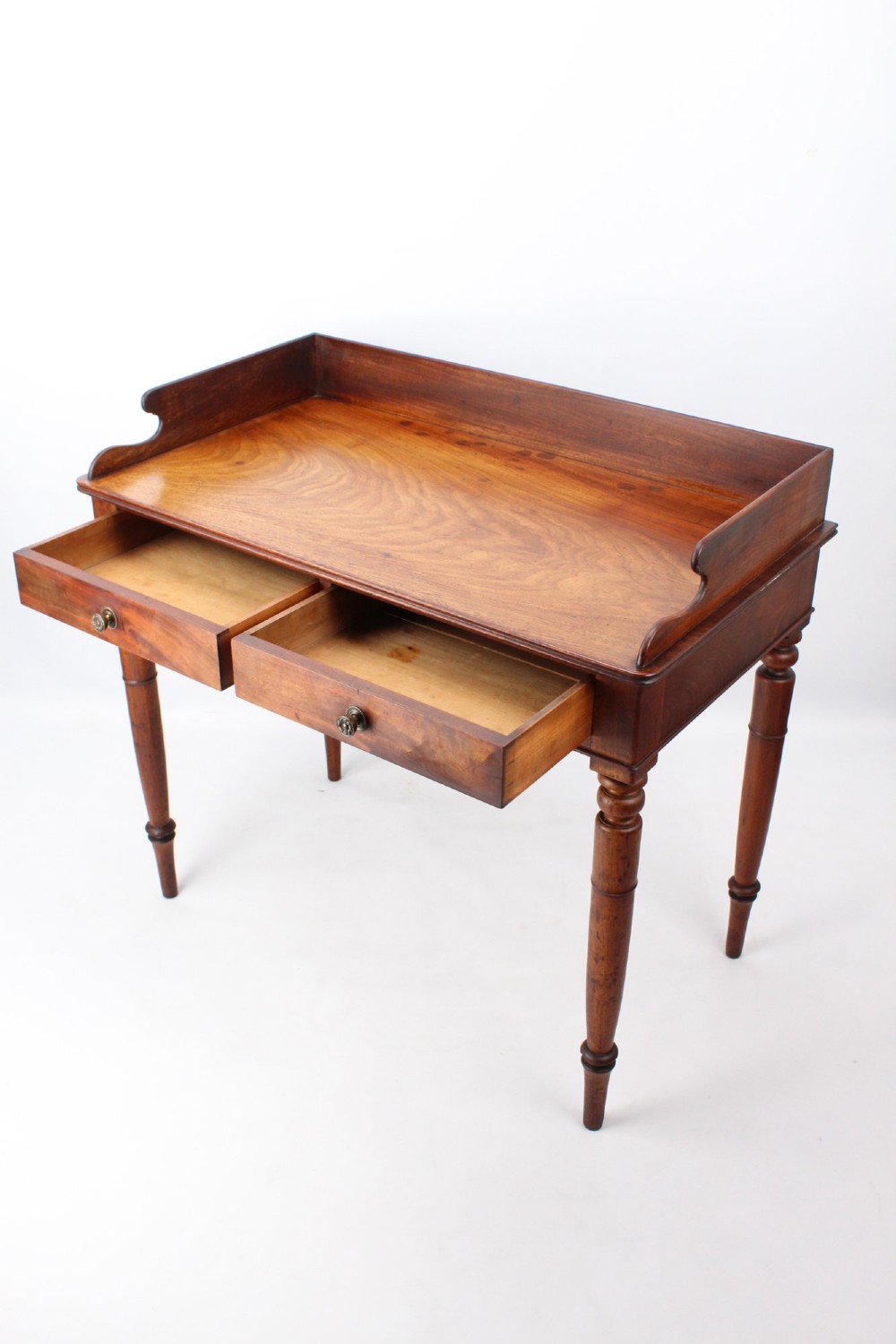 A Victorian mahogany writing table featuring a low gallery back top, two frieze drawers with decorative handles, and four turned legs. View III