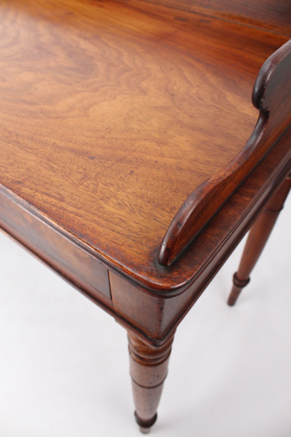 A Victorian mahogany writing table featuring a low gallery back top, two frieze drawers with decorative handles, and four turned legs. View VII