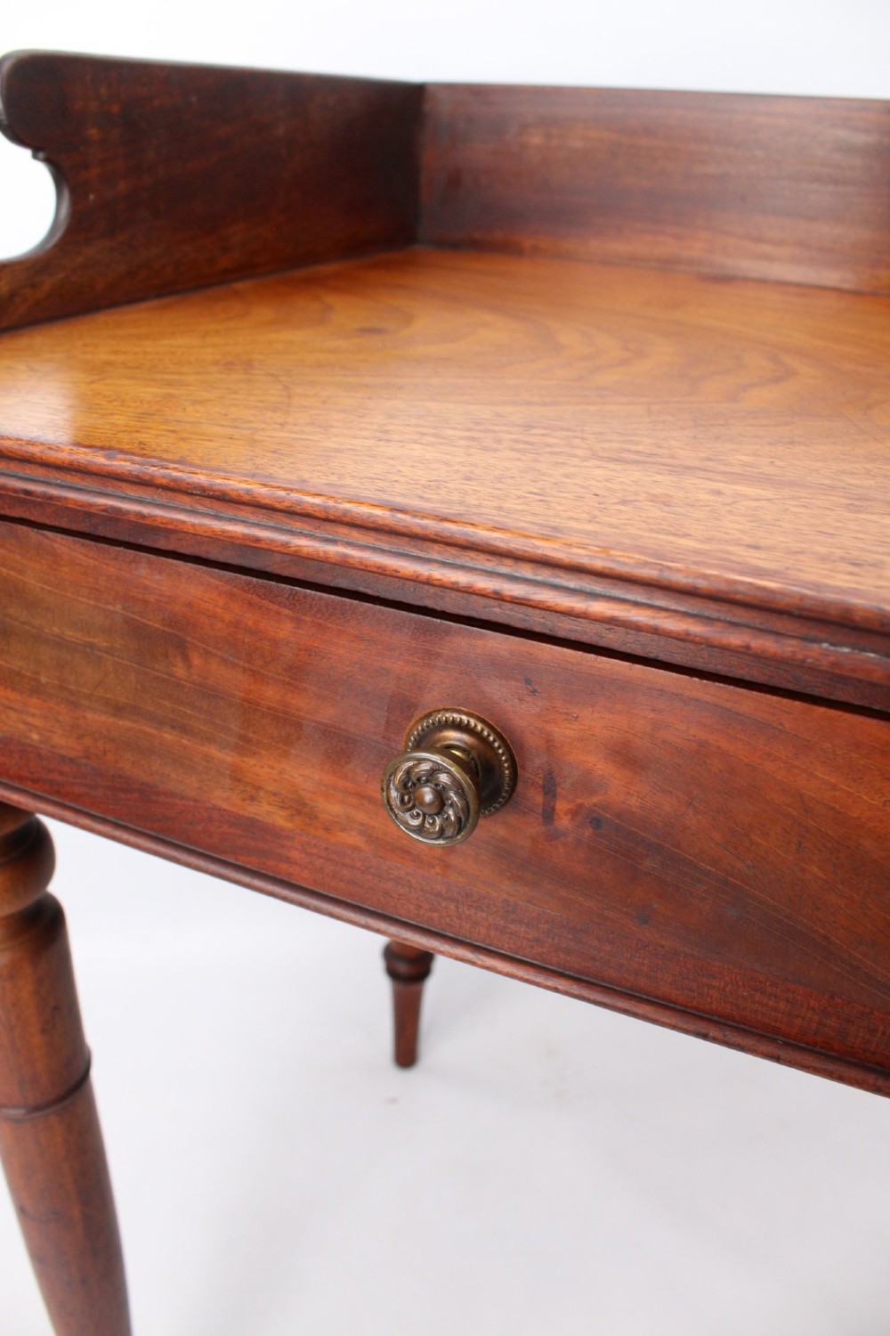 A Victorian mahogany writing table featuring a low gallery back top, two frieze drawers with decorative handles, and four turned legs. View VIII