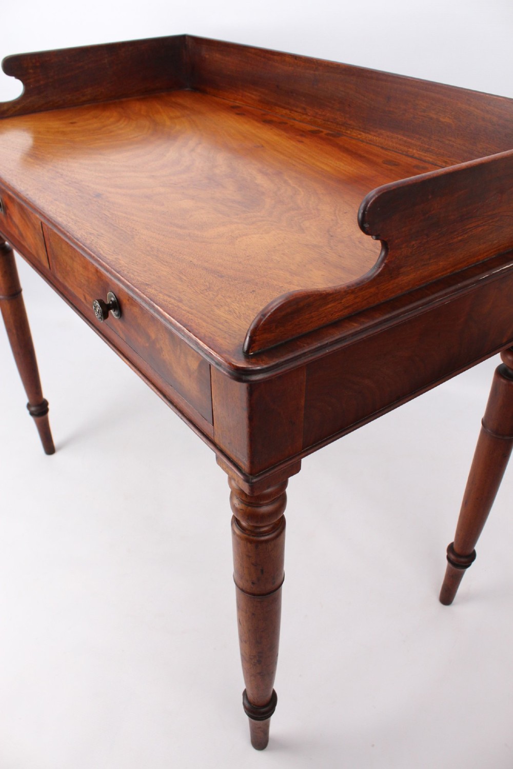 A Victorian mahogany writing table featuring a low gallery back top, two frieze drawers with decorative handles, and four turned legs. View IX