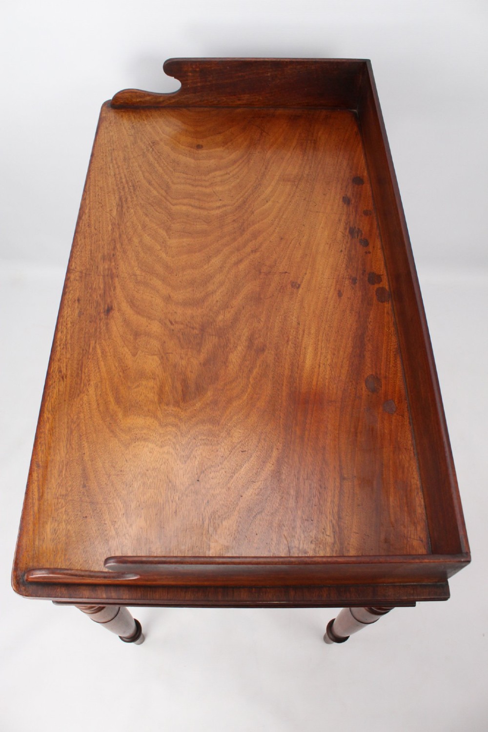 A Victorian mahogany writing table featuring a low gallery back top, two frieze drawers with decorative handles, and four turned legs. View X