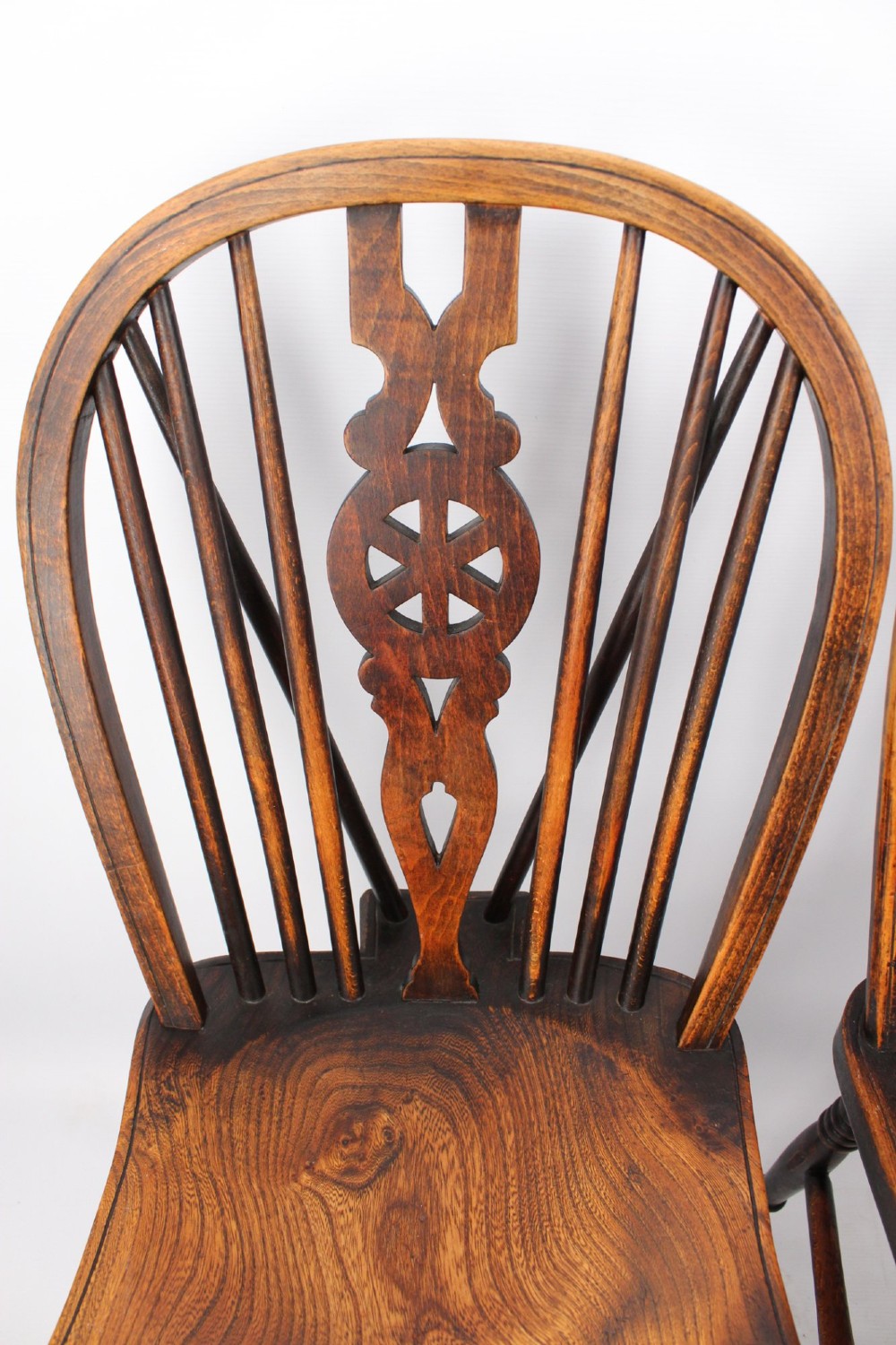 A near pair of antique dark timber Windsor kitchen chairs featuring pierced wheelback splats, contoured saddle seats, and turned legs. View IV