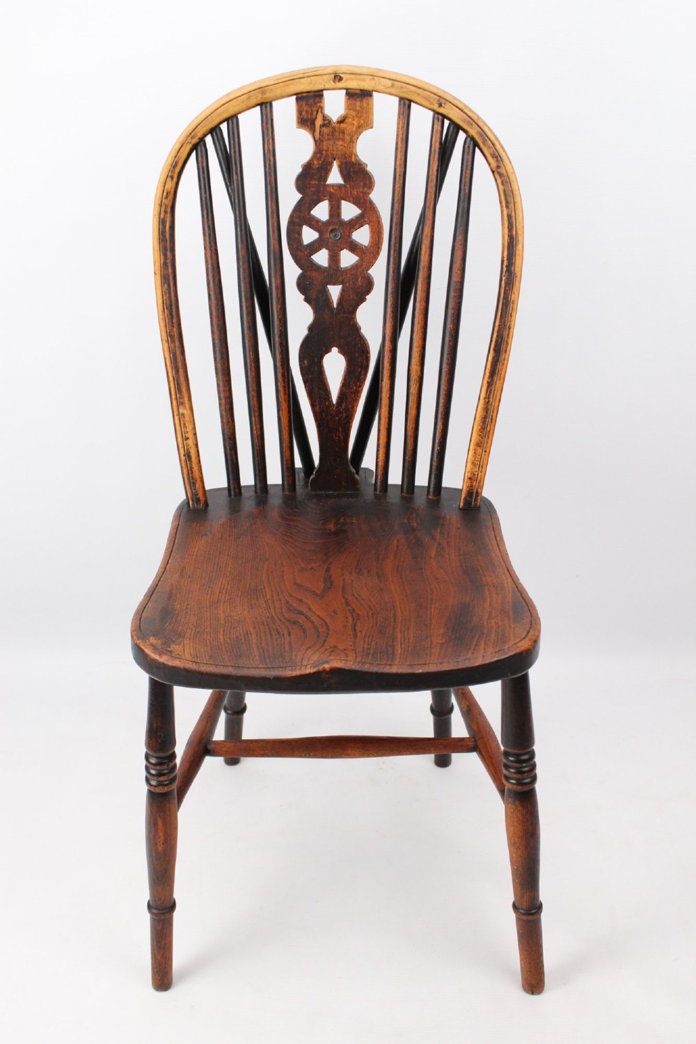 A near pair of antique dark timber Windsor kitchen chairs featuring pierced wheelback splats, contoured saddle seats, and turned legs. View VIII