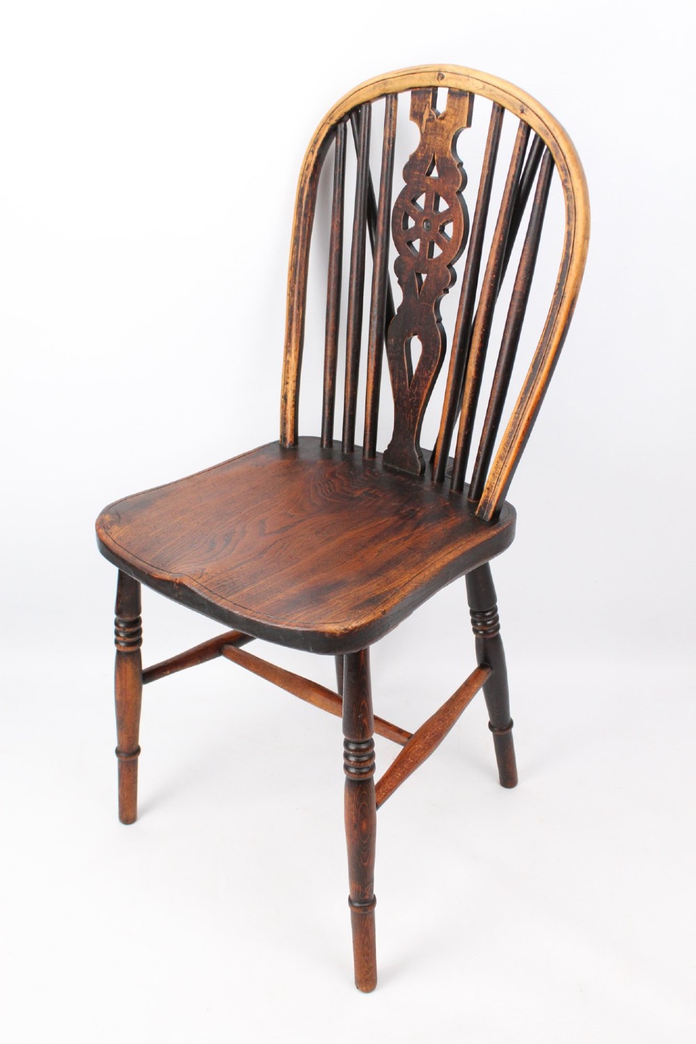 A near pair of antique dark timber Windsor kitchen chairs featuring pierced wheelback splats, contoured saddle seats, and turned legs. View IX