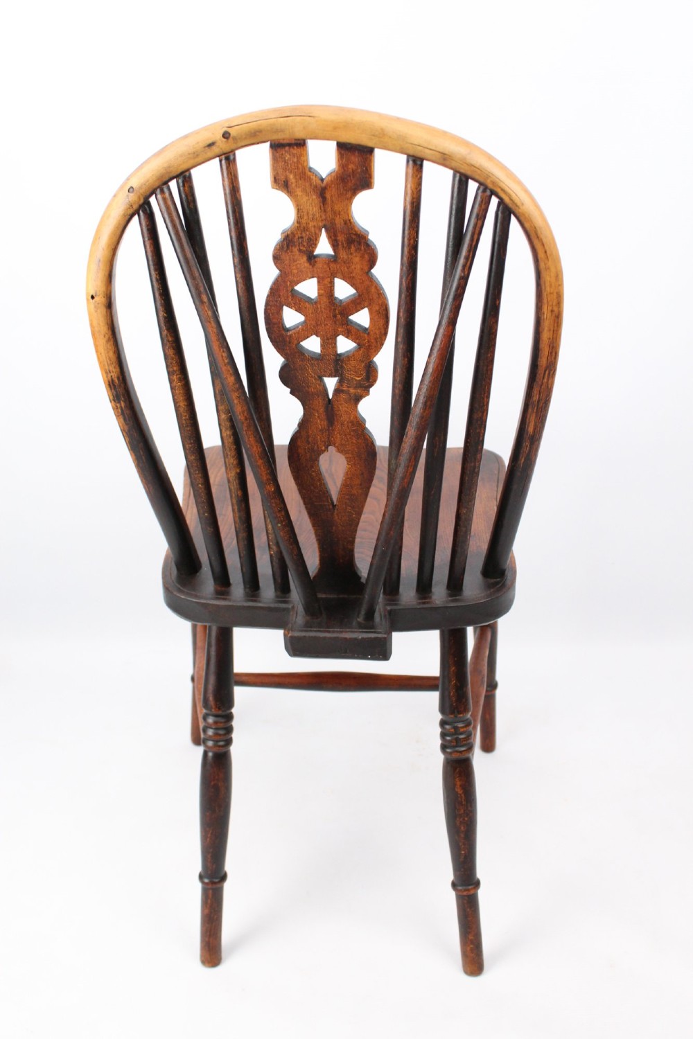 A near pair of antique dark timber Windsor kitchen chairs featuring pierced wheelback splats, contoured saddle seats, and turned legs. View XI