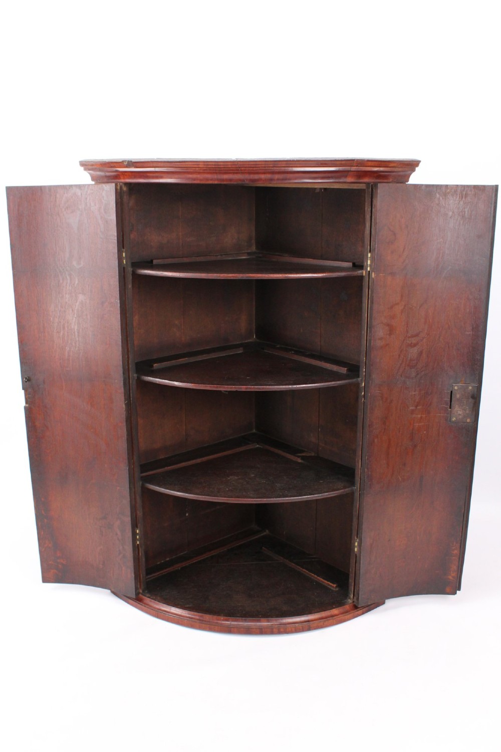 An 18th-century Georgian oak corner cupboard featuring a curved bow front, brass H-hinges, keyhole escutcheon plates, and mahogany crossbanding. View III