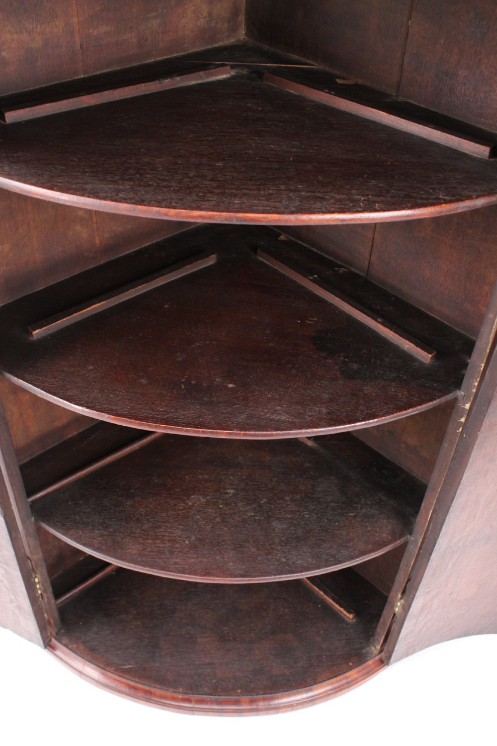 An 18th-century Georgian oak corner cupboard featuring a curved bow front, brass H-hinges, keyhole escutcheon plates, and mahogany crossbanding. View IV