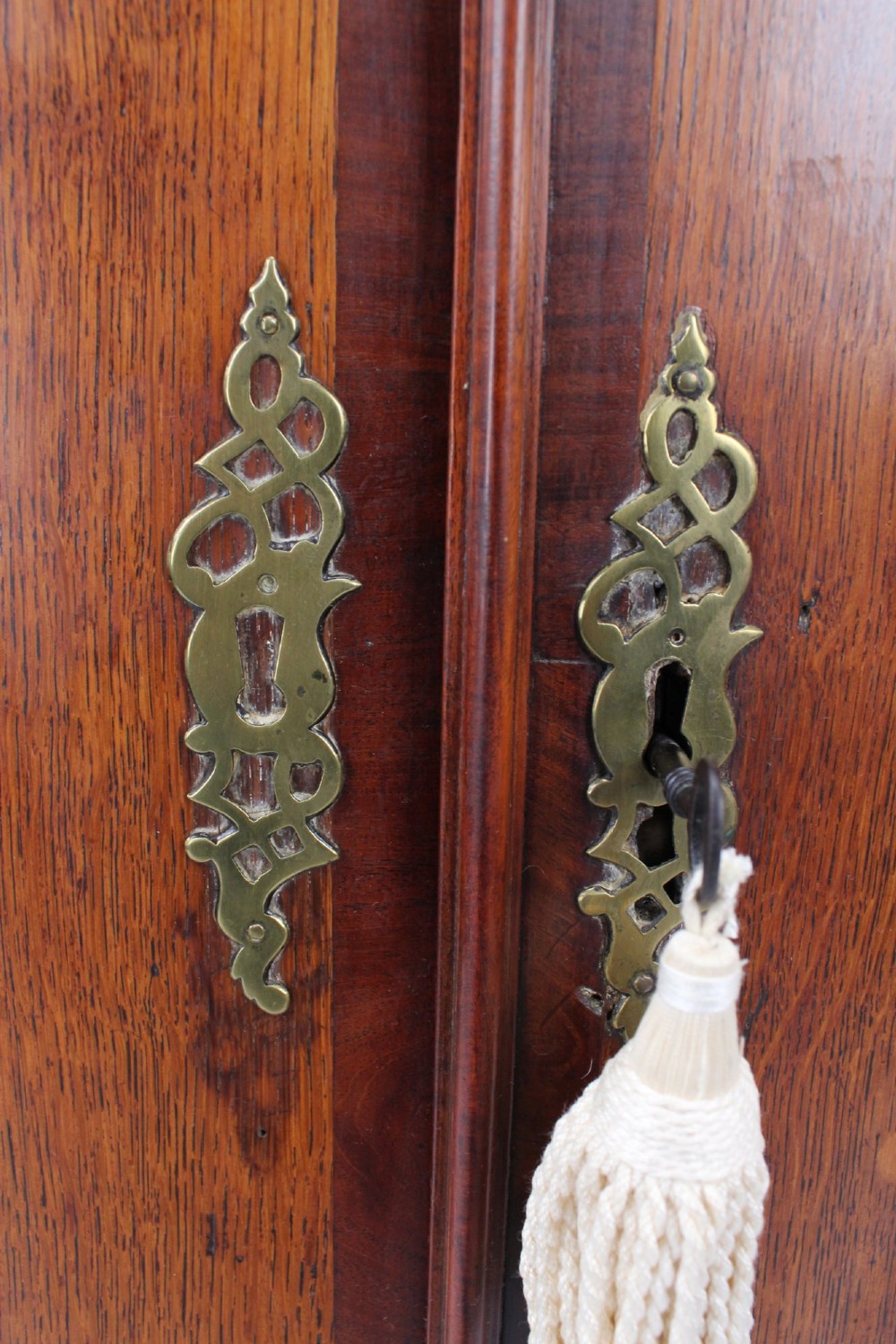 An 18th-century Georgian oak corner cupboard featuring a curved bow front, brass H-hinges, keyhole escutcheon plates, and mahogany crossbanding. View VIII