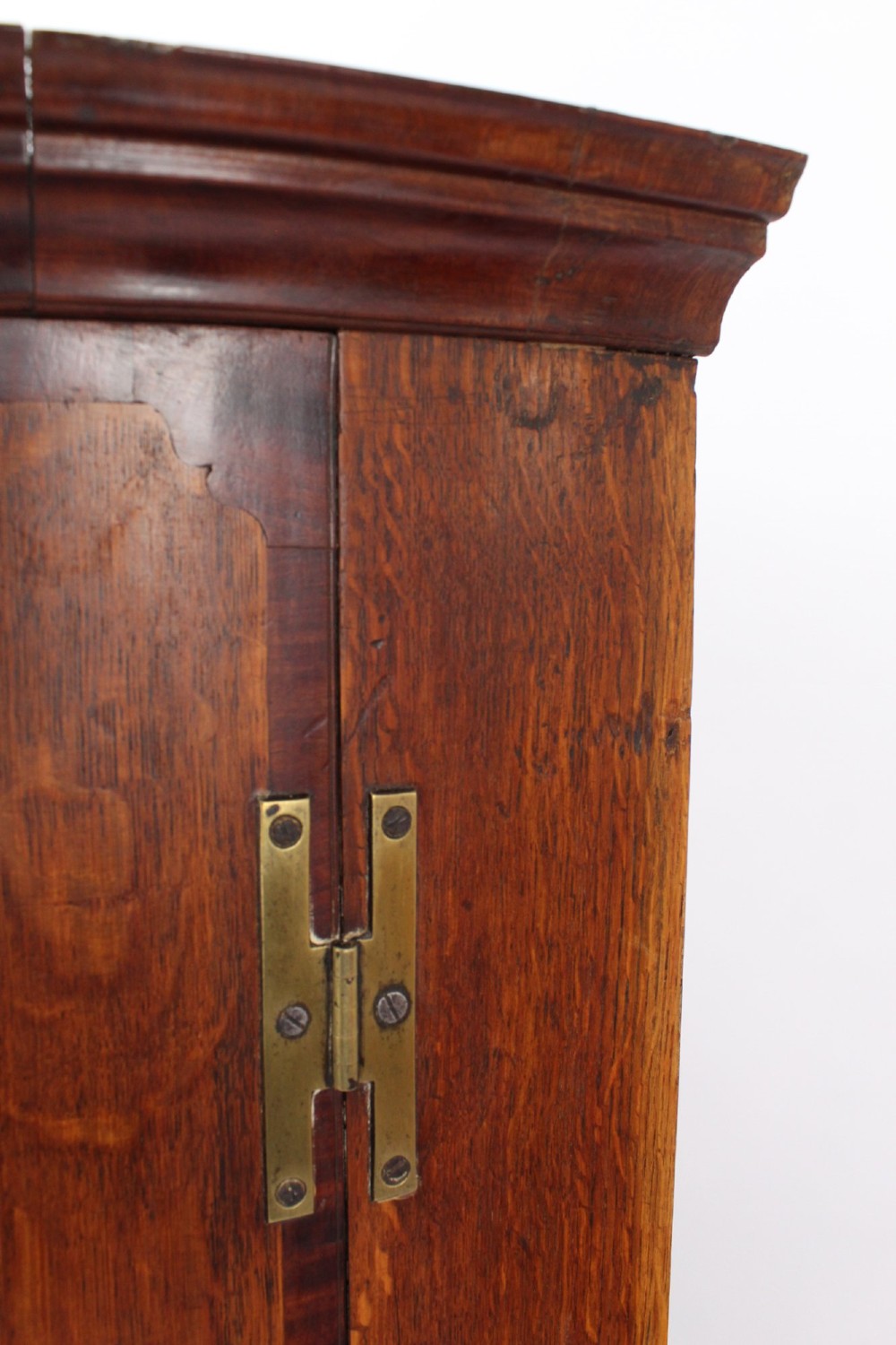 An 18th-century Georgian oak corner cupboard featuring a curved bow front, brass H-hinges, keyhole escutcheon plates, and mahogany crossbanding. View X
