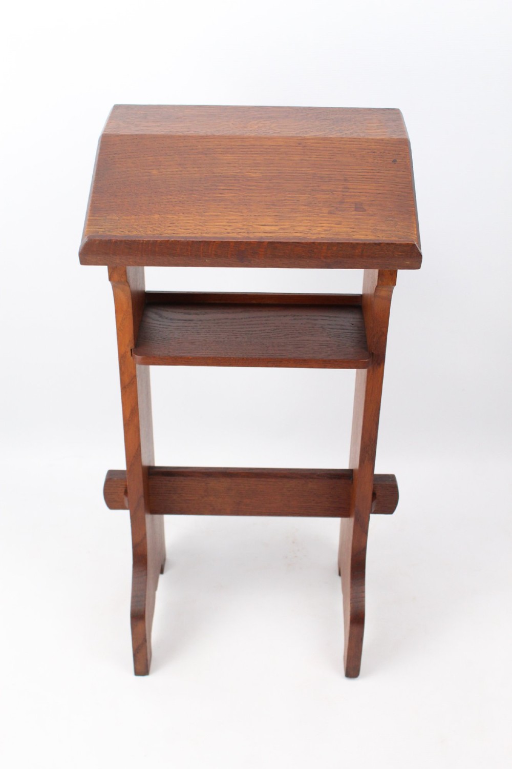 An Edwardian Arts and Crafts solid oak lectern featuring an angled reading top, an open middle shelf, and visible wedge tenon joinery. View III