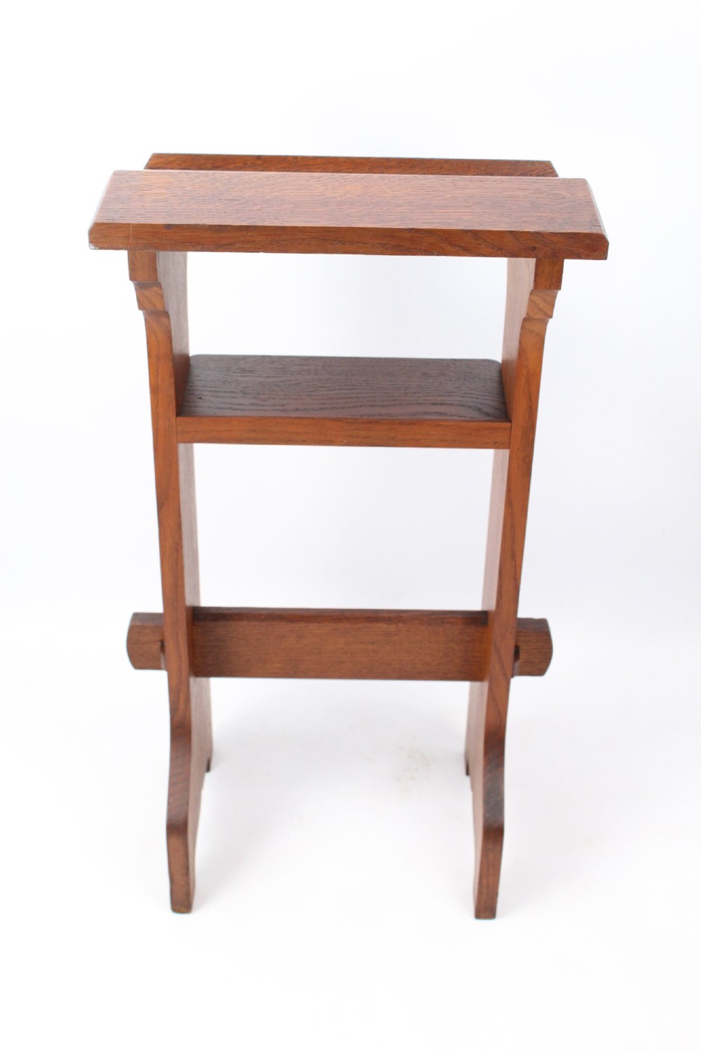 An Edwardian Arts and Crafts solid oak lectern featuring an angled reading top, an open middle shelf, and visible wedge tenon joinery. View V
