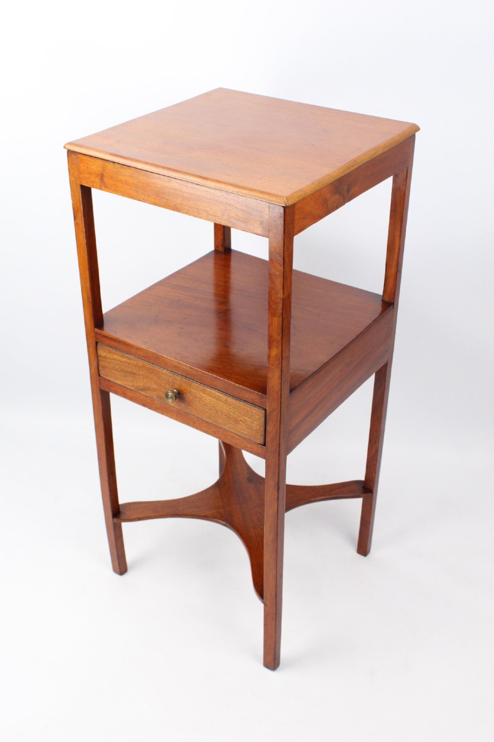 A two-tier Georgian mahogany bedside table with a single drawer, square top, and curved X-form stretcher.