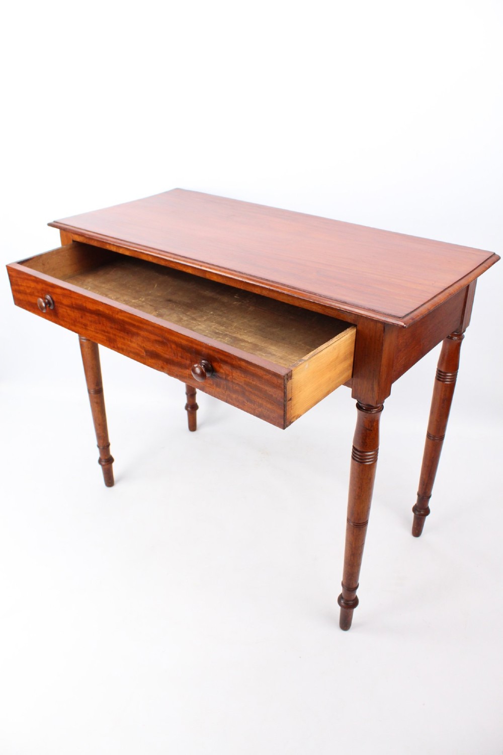 A Victorian mahogany writing table featuring a long frieze drawer with two turned wooden knobs, elevated on four ring-turned tapered legs. View III