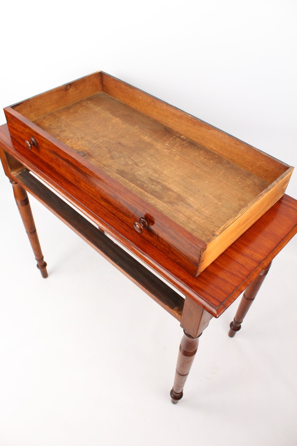 A Victorian mahogany writing table featuring a long frieze drawer with two turned wooden knobs, elevated on four ring-turned tapered legs. View IV
