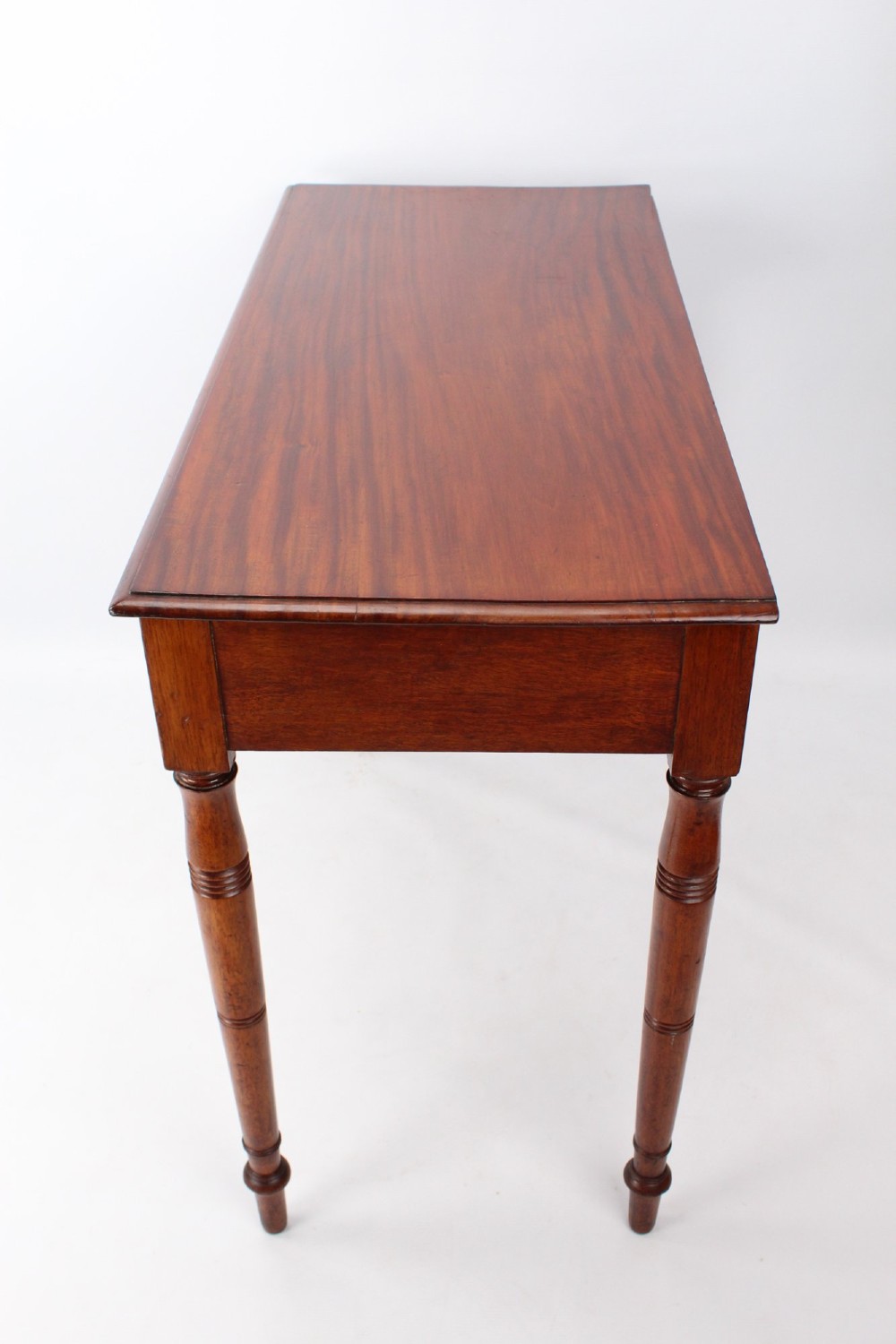A Victorian mahogany writing table featuring a long frieze drawer with two turned wooden knobs, elevated on four ring-turned tapered legs. View VI