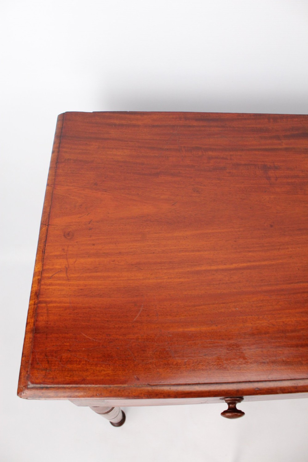 A Victorian mahogany writing table featuring a long frieze drawer with two turned wooden knobs, elevated on four ring-turned tapered legs. View X
