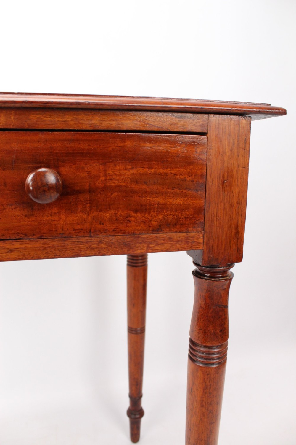 A Victorian mahogany writing table featuring a long frieze drawer with two turned wooden knobs, elevated on four ring-turned tapered legs. View XII