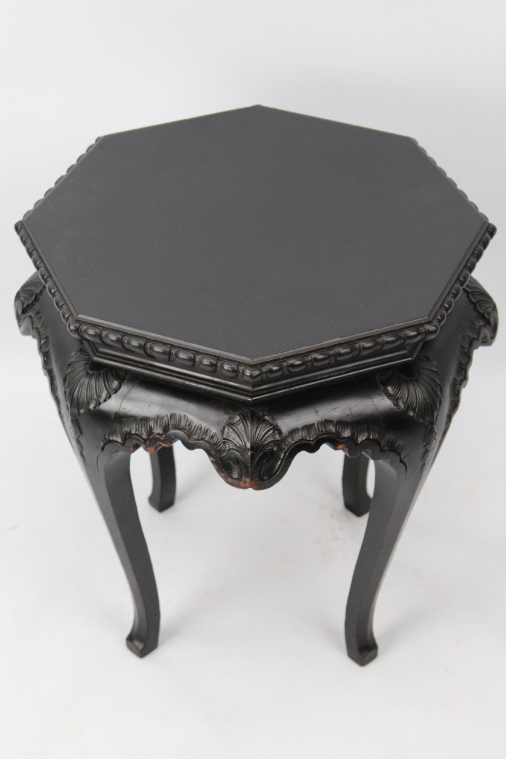An antique ebonised hexagonal wooden coffee table featuring carved shell details along the apron and cabriole legs against a white background. View II