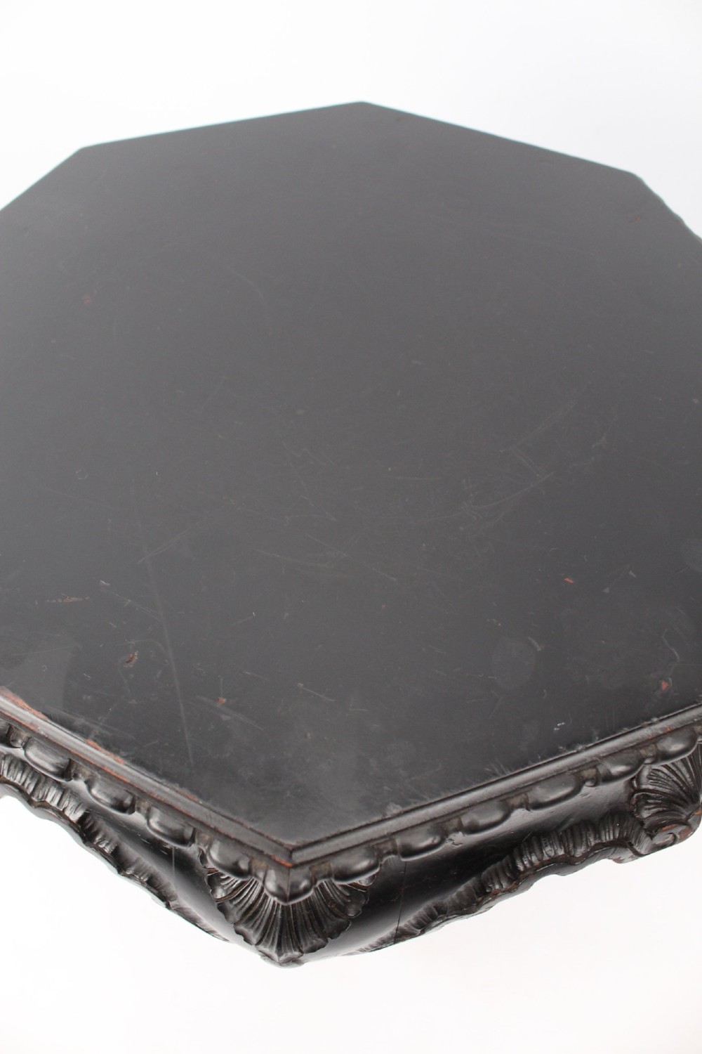 An antique ebonised hexagonal wooden coffee table featuring carved shell details along the apron and cabriole legs against a white background. View VI