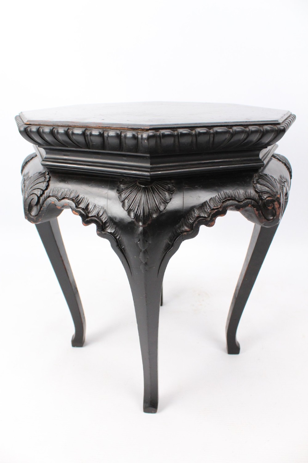 An antique ebonised hexagonal wooden coffee table featuring carved shell details along the apron and cabriole legs against a white background. View VII