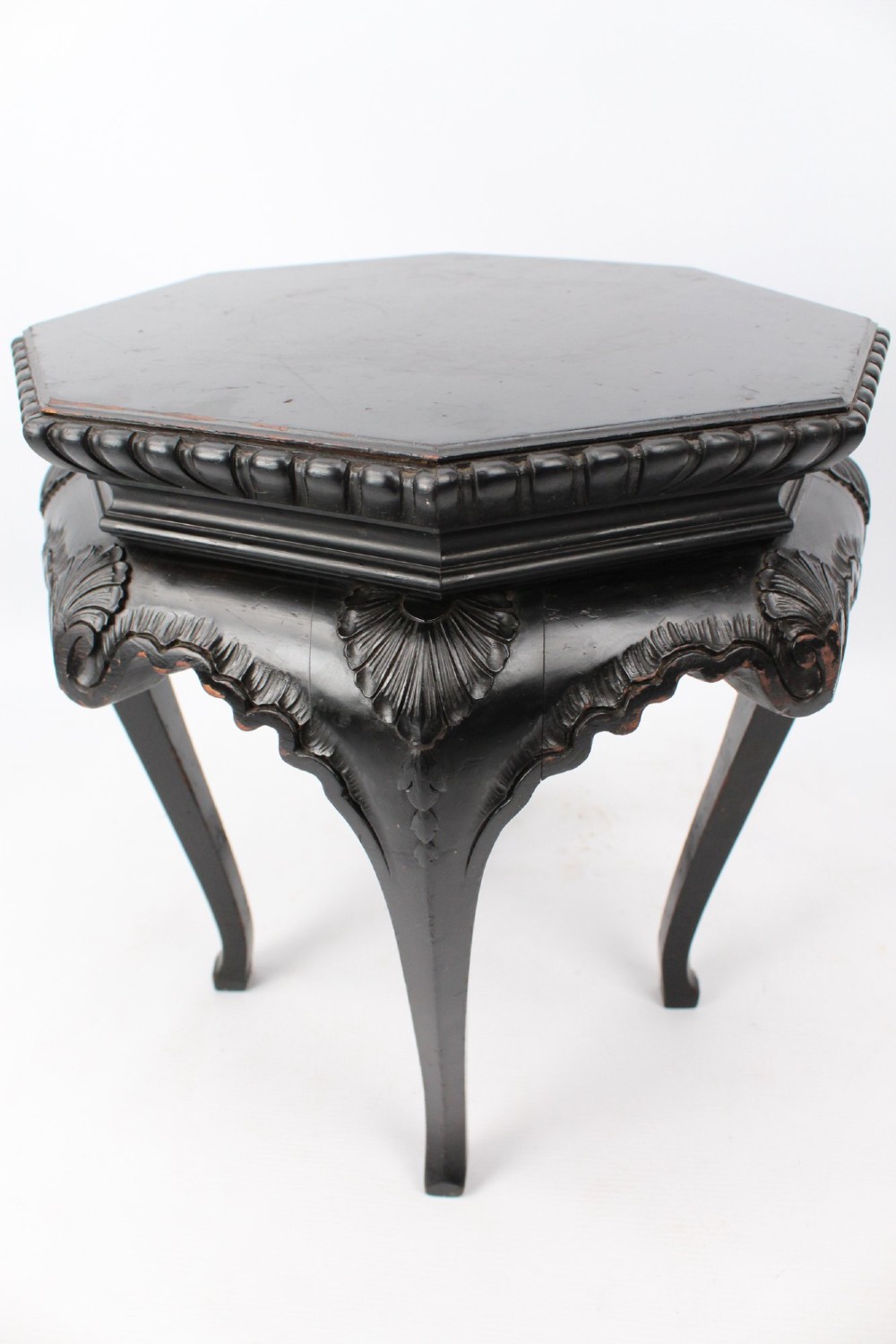 An antique ebonised hexagonal wooden coffee table featuring carved shell details along the apron and cabriole legs against a white background. View VIII