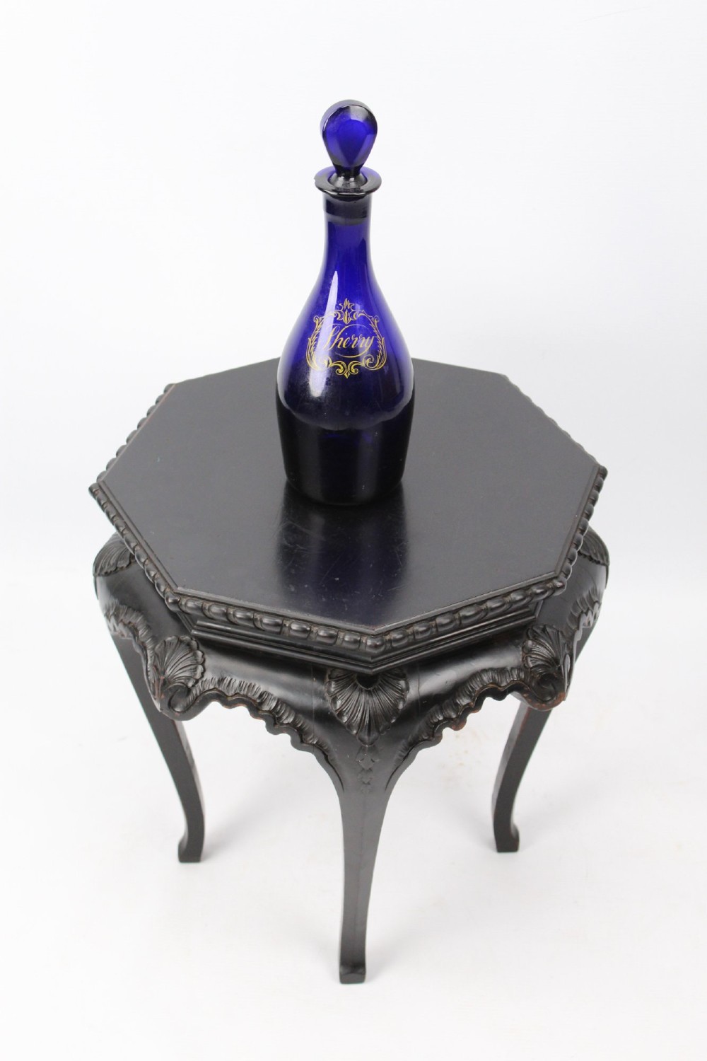 An antique ebonised hexagonal wooden coffee table featuring carved shell details along the apron and cabriole legs against a white background. View XIII