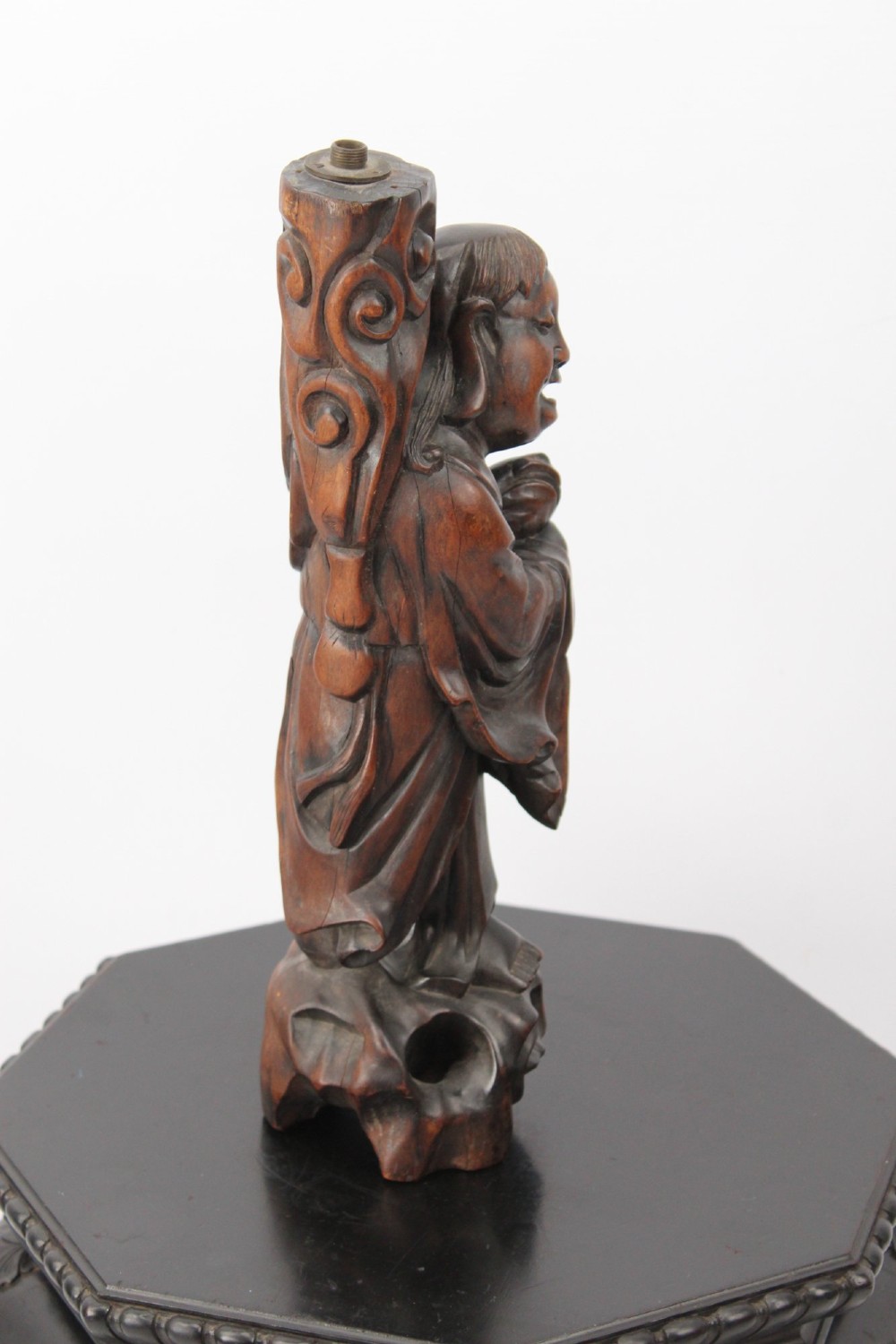 A hand-carved dark wood figure of the Daoist Immortal Liu Hai holding a three-legged toad, set upon a carved rockwork base with a brass lamp fitting at the top. View II
