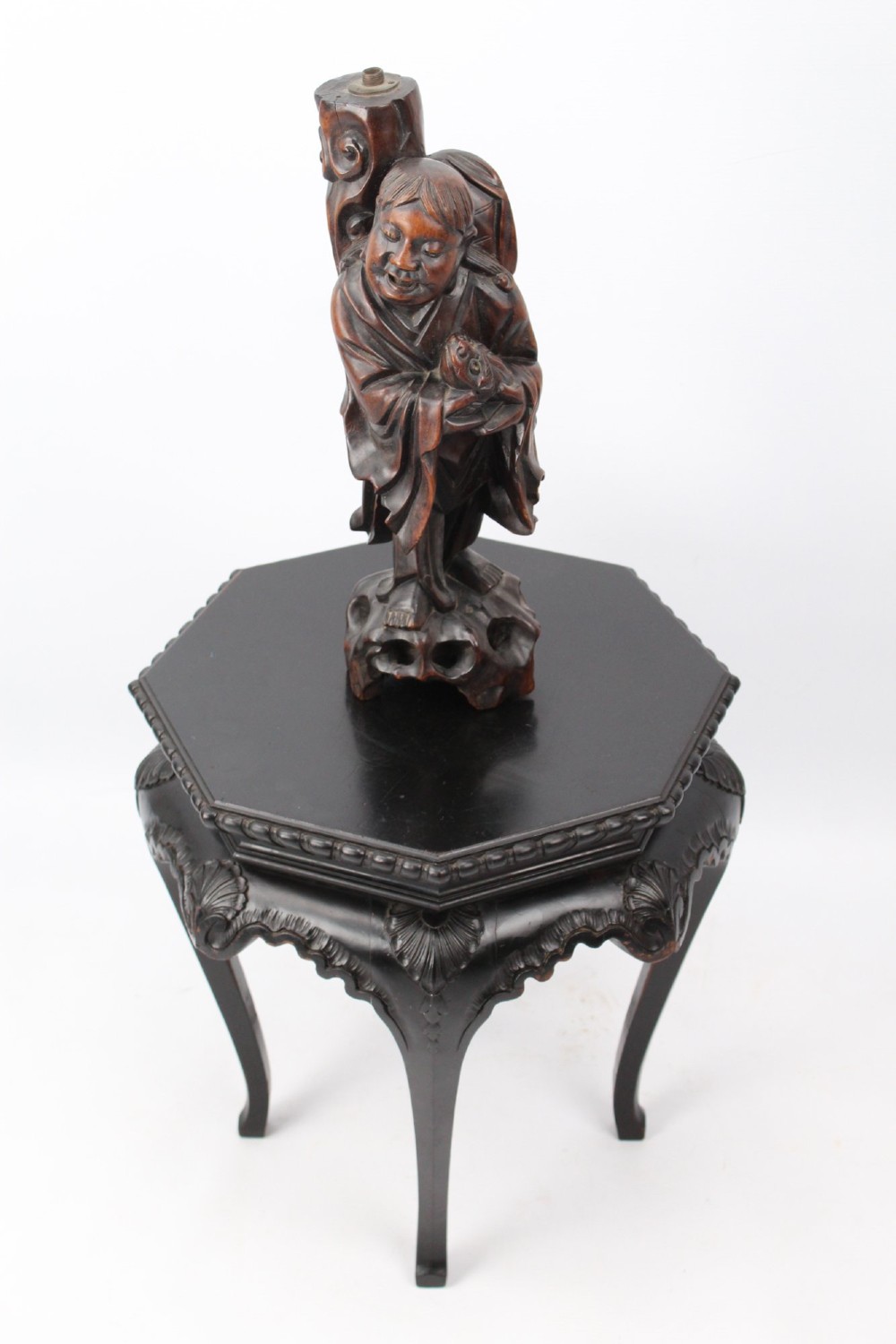 A hand-carved dark wood figure of the Daoist Immortal Liu Hai holding a three-legged toad, set upon a carved rockwork base with a brass lamp fitting at the top. View XIII
