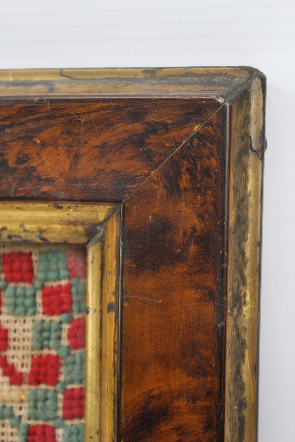 A framed 1875 Victorian needlework sampler featuring rows of embroidered alphabets, geometric borders, and text reading Mary J Garbutt Aged 12 Years inside a wooden frame. View VI