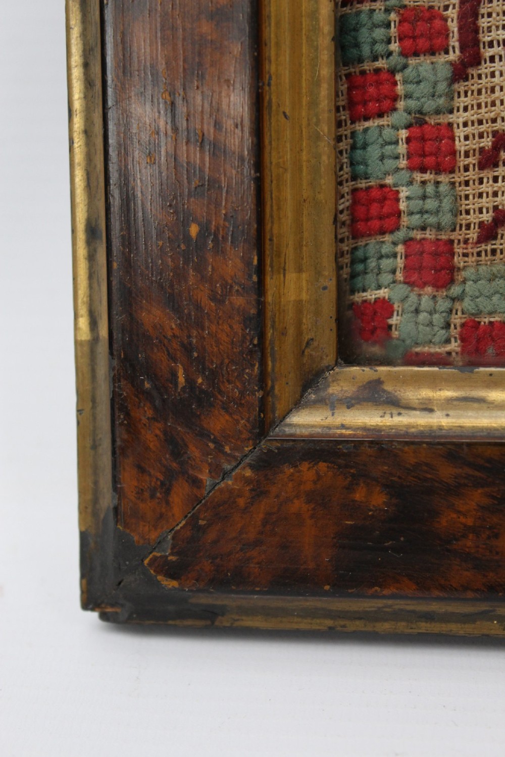A framed 1875 Victorian needlework sampler featuring rows of embroidered alphabets, geometric borders, and text reading Mary J Garbutt Aged 12 Years inside a wooden frame. View VII
