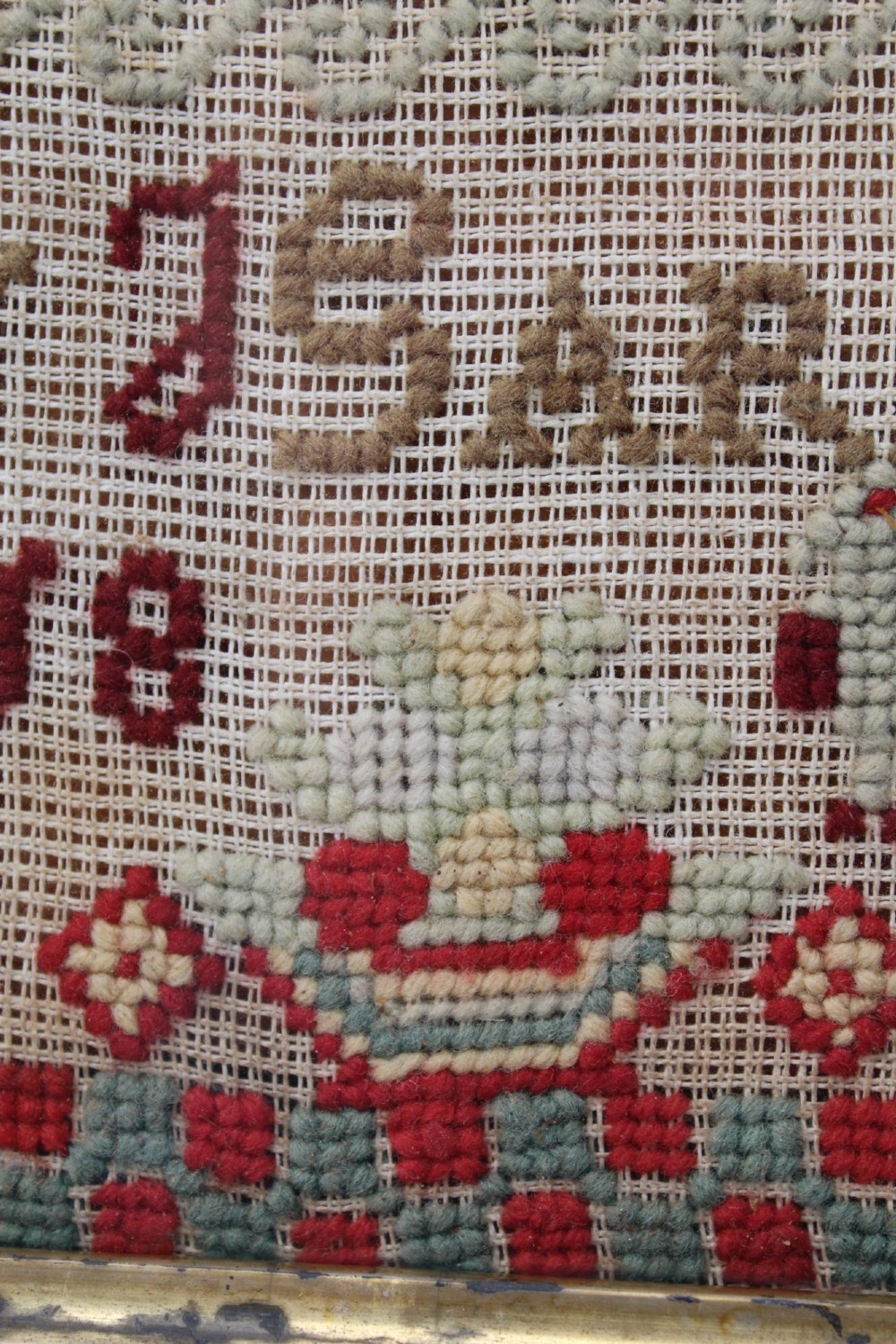A framed 1875 Victorian needlework sampler featuring rows of embroidered alphabets, geometric borders, and text reading Mary J Garbutt Aged 12 Years inside a wooden frame. View XI
