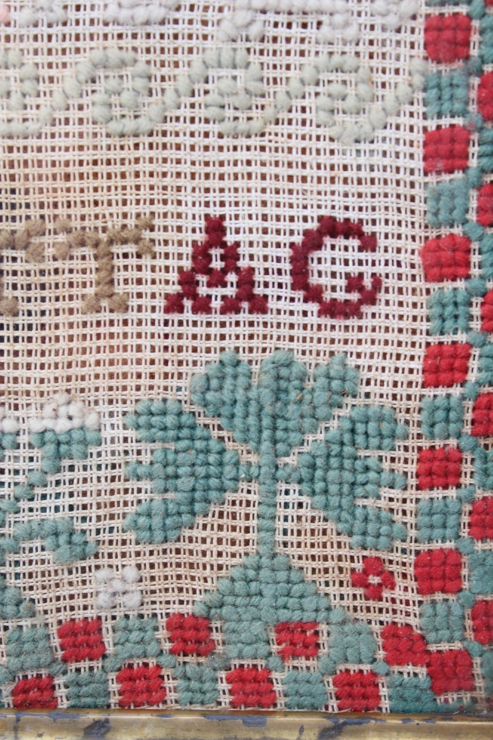 A framed 1875 Victorian needlework sampler featuring rows of embroidered alphabets, geometric borders, and text reading Mary J Garbutt Aged 12 Years inside a wooden frame. View XII