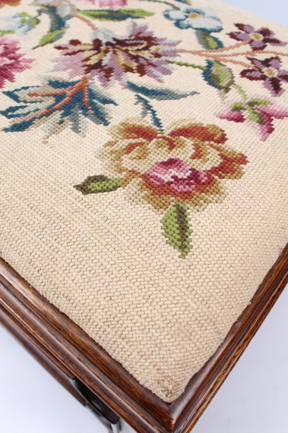 A low rectangular dark mahogany storage ottoman featuring a beige upholstered top with floral needlework embroidery. View VI
