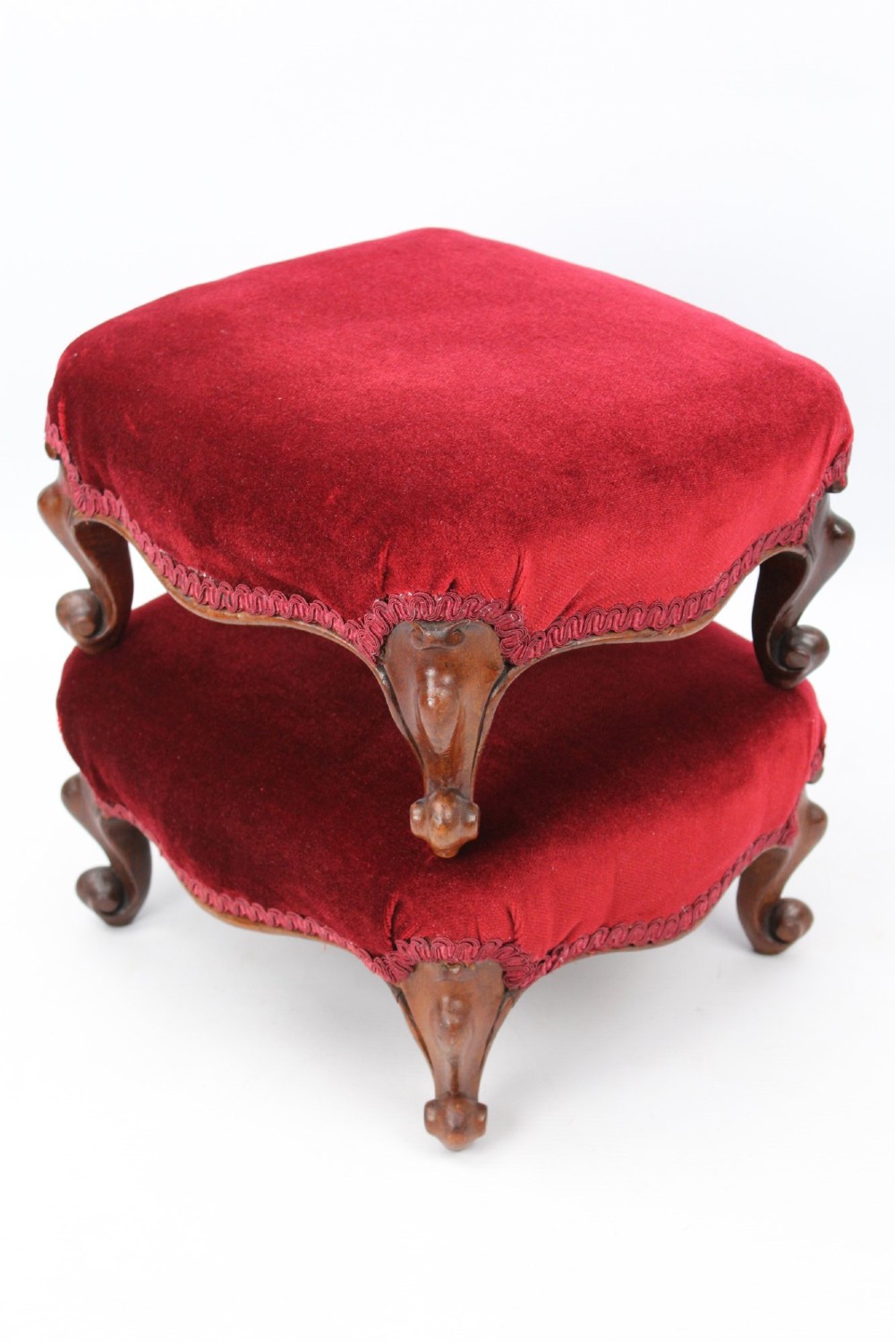 A pair of small Victorian footstools featuring crimson red velvet upholstery and carved walnut cabriole feet. View II