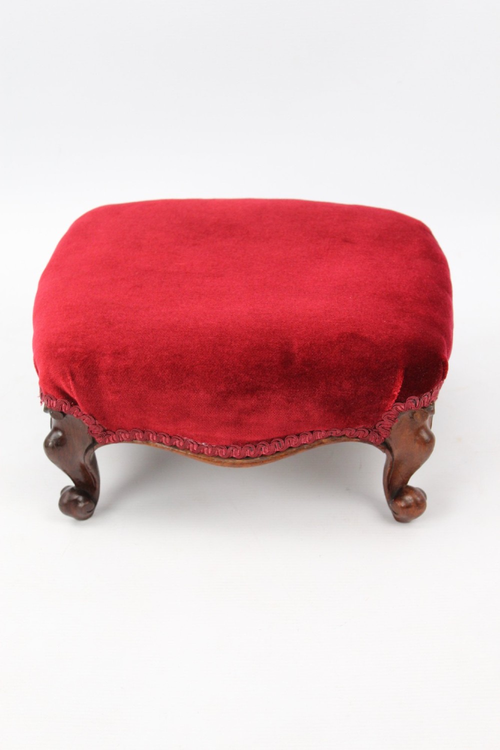 A pair of small Victorian footstools featuring crimson red velvet upholstery and carved walnut cabriole feet. View VI