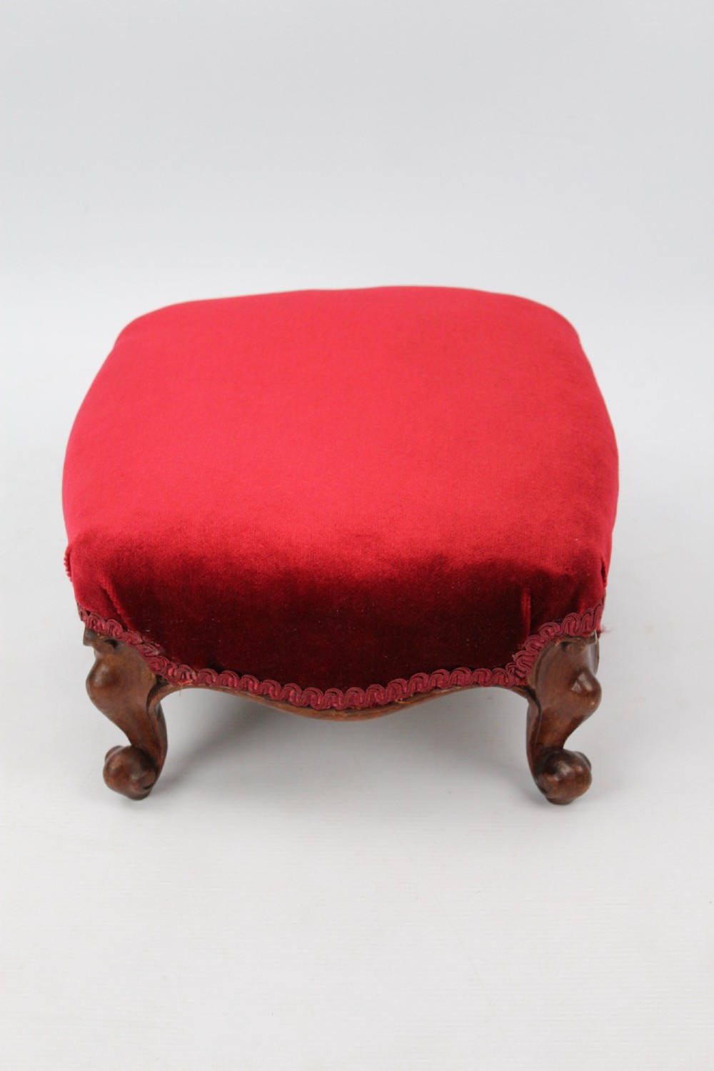 A pair of small Victorian footstools featuring crimson red velvet upholstery and carved walnut cabriole feet. View VII