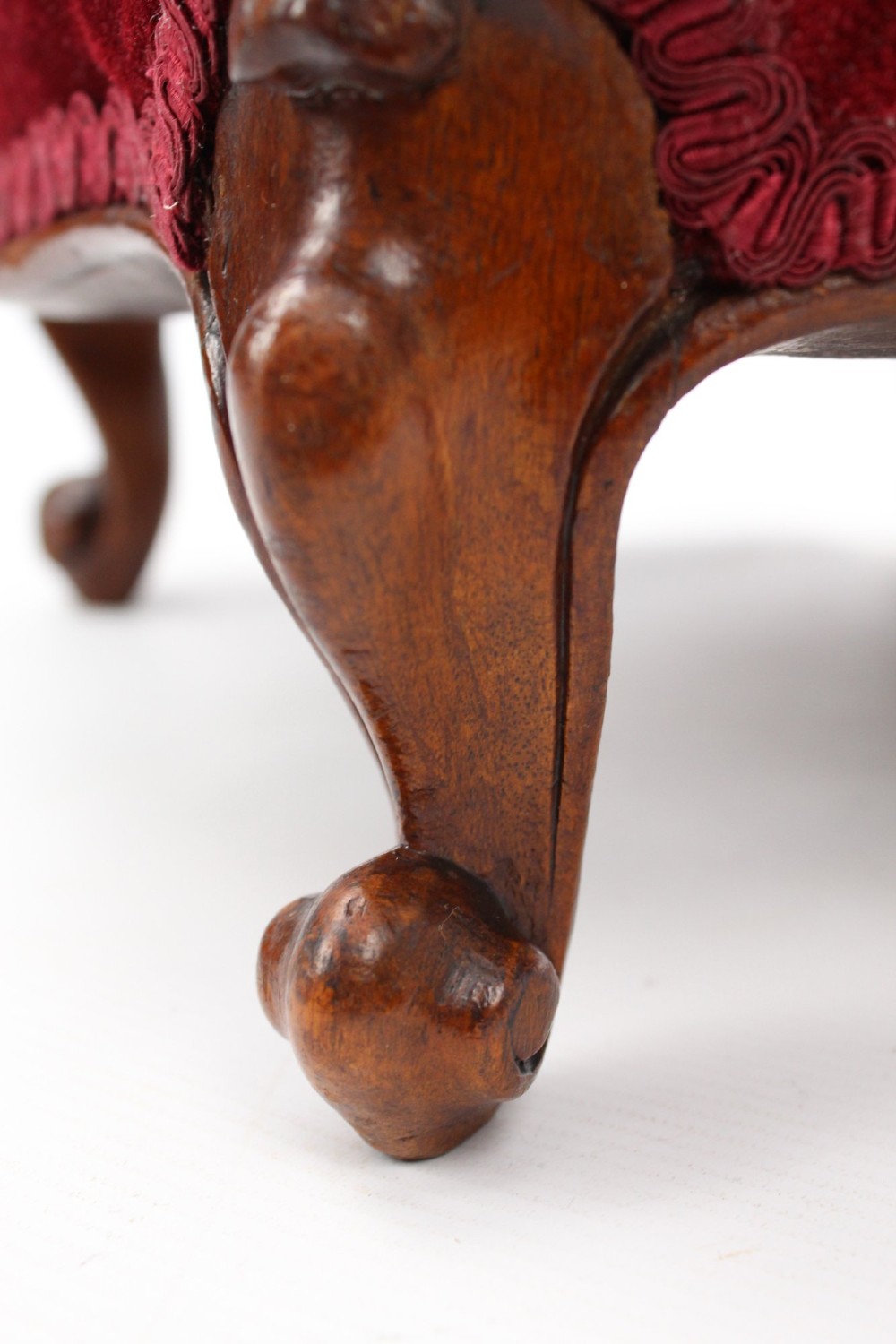 A pair of small Victorian footstools featuring crimson red velvet upholstery and carved walnut cabriole feet. View XII