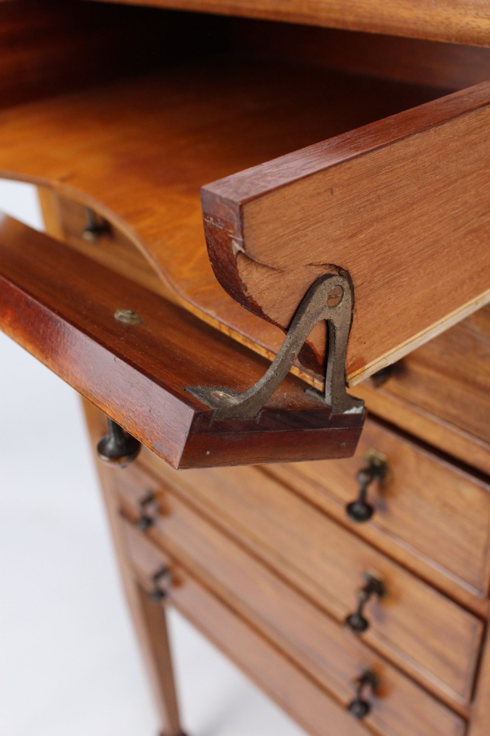 An Edwardian mahogany music cabinet featuring six shallow drawers with brass handles, set on slender square tapered legs with a raised gallery back. View VII
