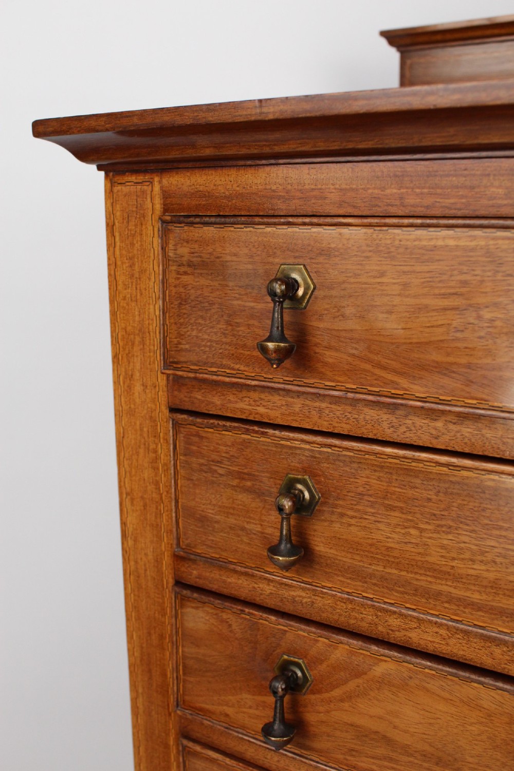 An Edwardian mahogany music cabinet featuring six shallow drawers with brass handles, set on slender square tapered legs with a raised gallery back. View VIII