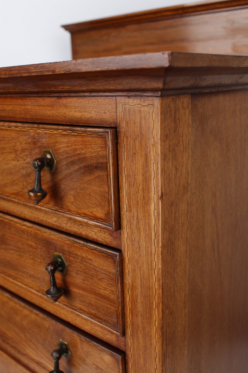 An Edwardian mahogany music cabinet featuring six shallow drawers with brass handles, set on slender square tapered legs with a raised gallery back. View IX