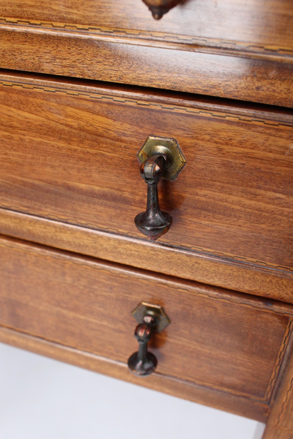 An Edwardian mahogany music cabinet featuring six shallow drawers with brass handles, set on slender square tapered legs with a raised gallery back. View X