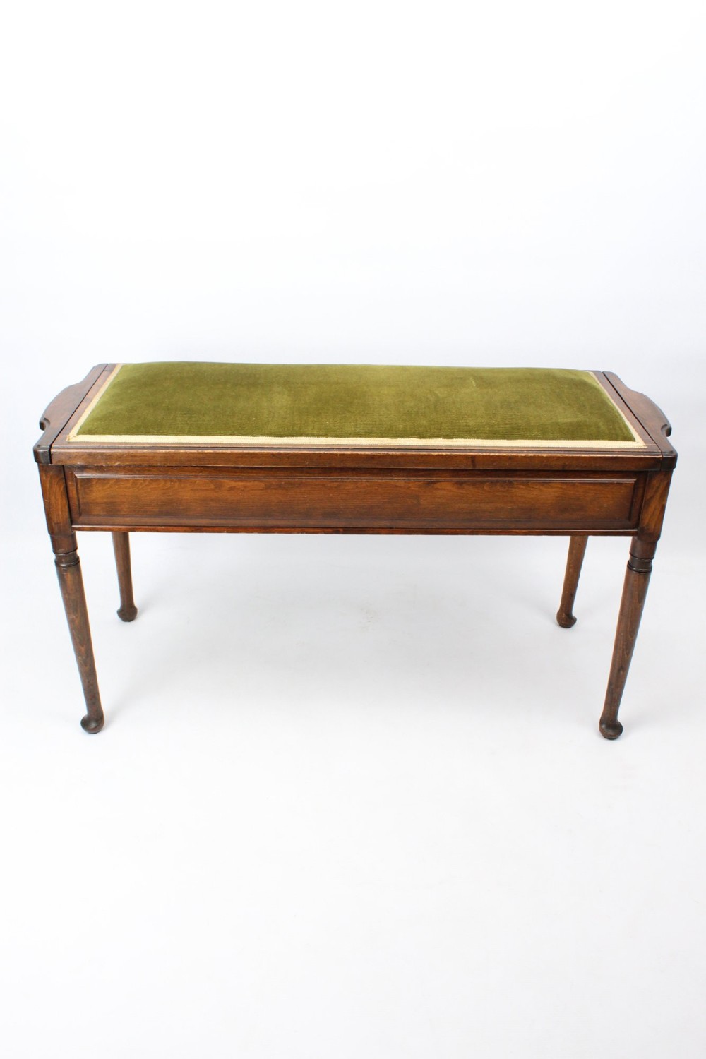 An Edwardian wooden duet piano stool featuring an olive green velvet upholstered seat and slender tapered legs. View II