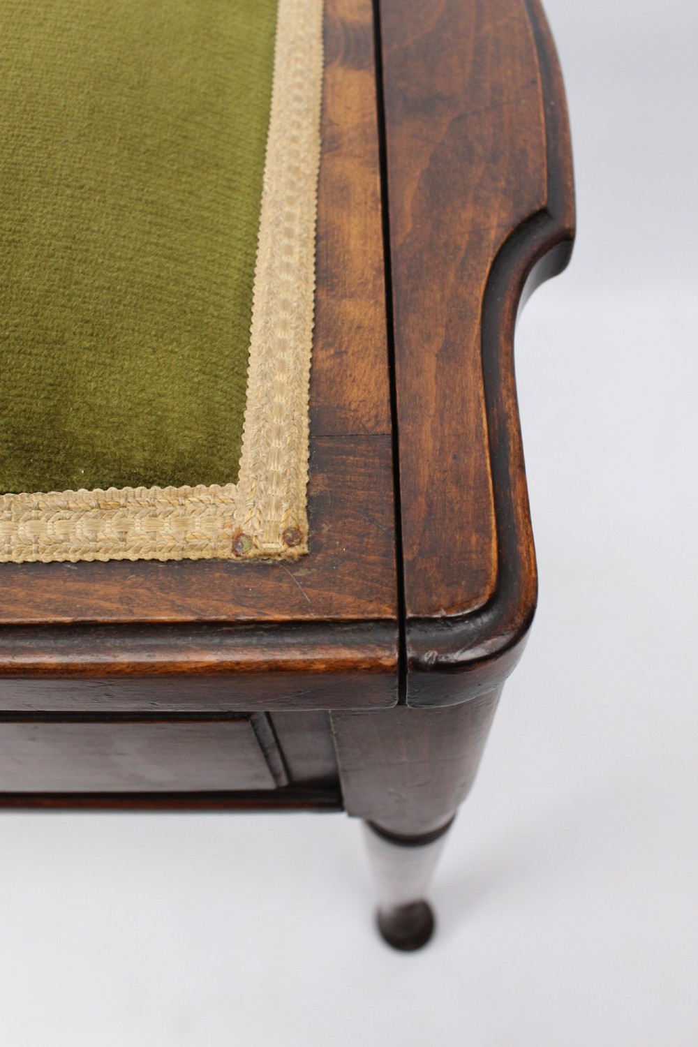 An Edwardian wooden duet piano stool featuring an olive green velvet upholstered seat and slender tapered legs. View XIII