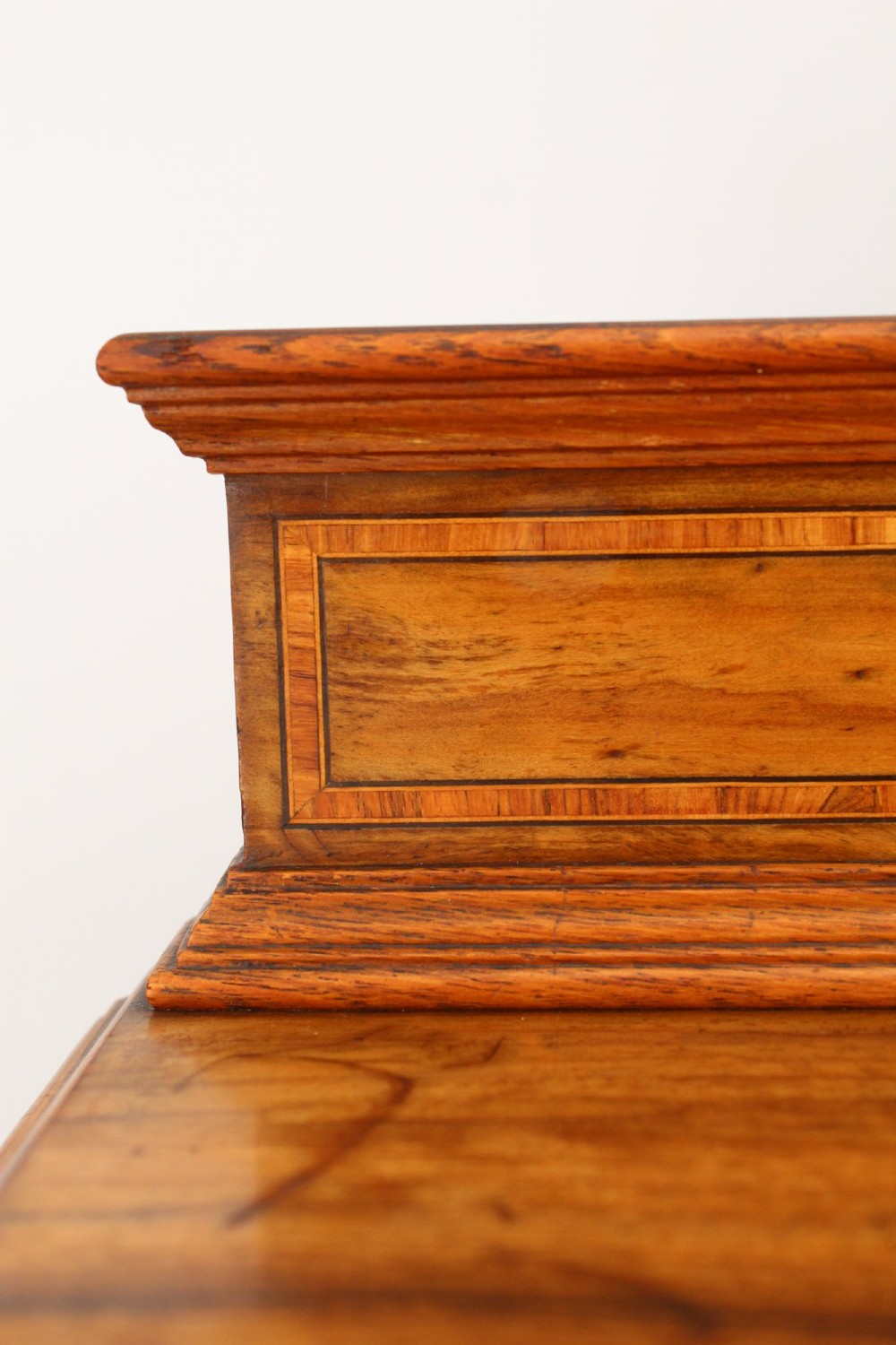 An Edwardian burr walnut bedside cabinet featuring a small gallery top, crossbanded inlaid door panel, drop brass handle, and square tapered legs. View XII
