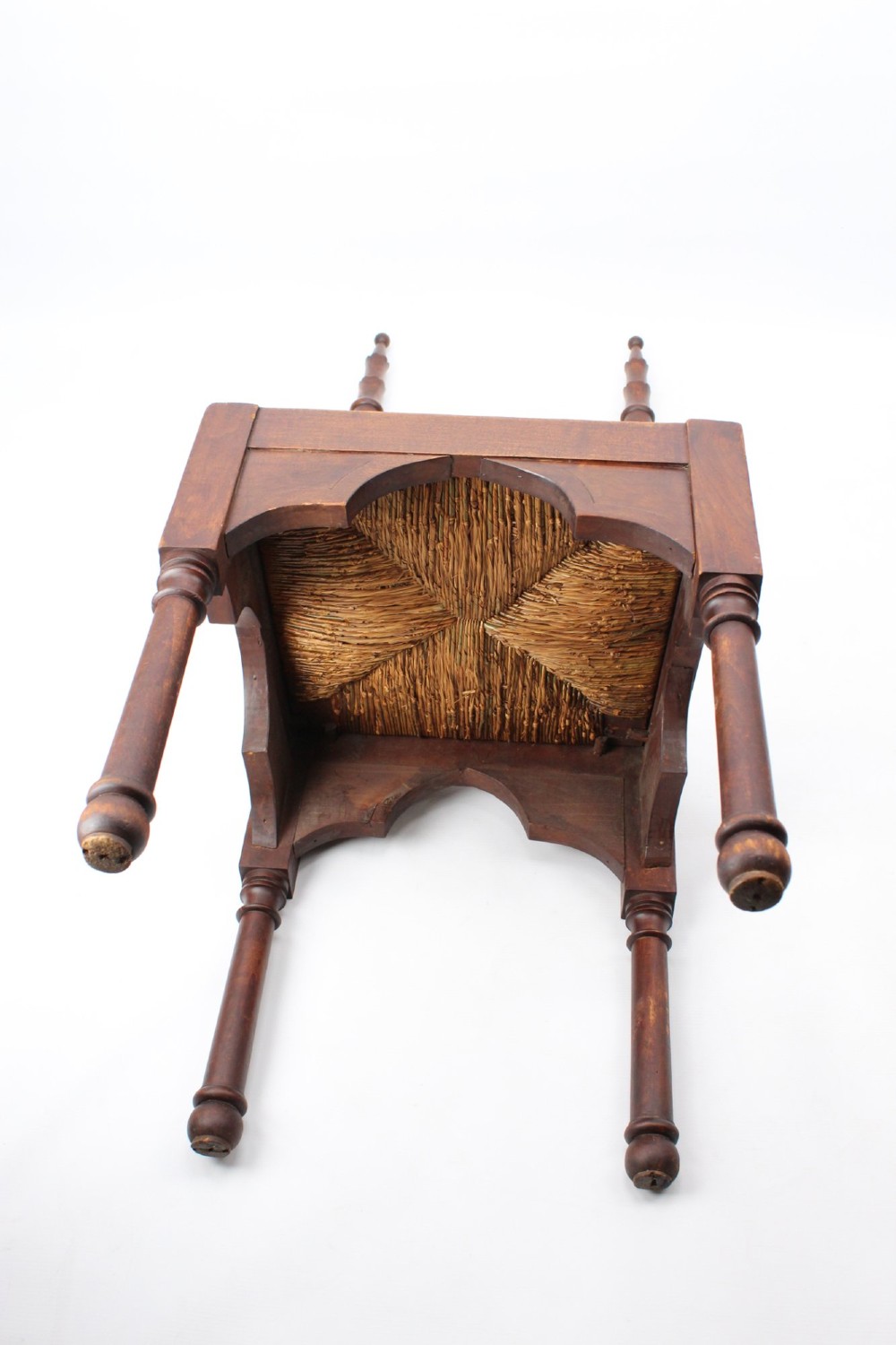 A Victorian Gothic Revival side chair made of dark oak with turned finials, a carved rectangular back panel, pointed arch aprons, and a woven rush seat. View V